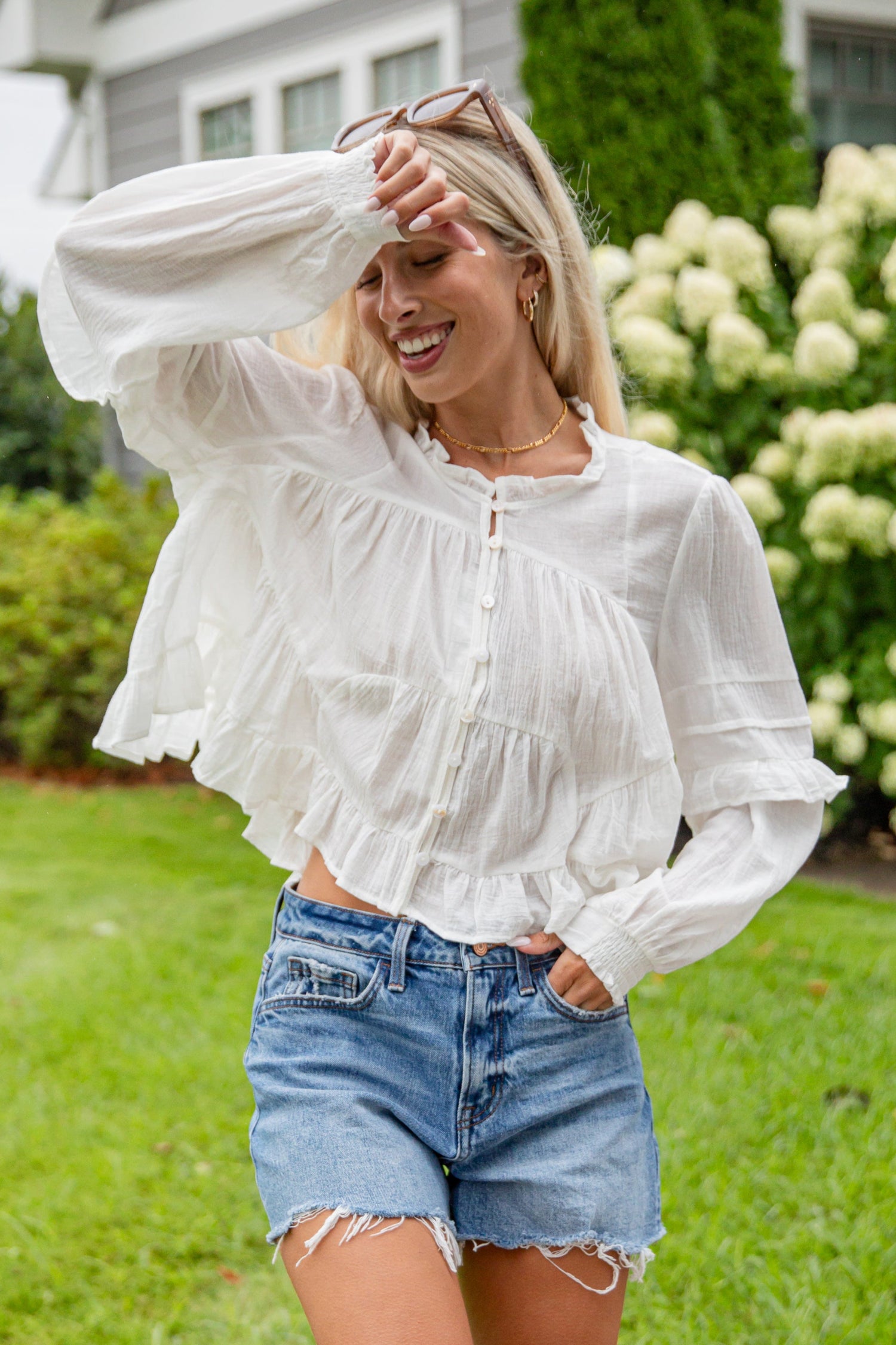 Woman in a white blouse and denim shorts standing in a garden