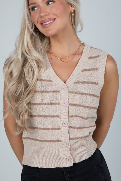 Woman wearing a beige striped sleeveless cardigan against a plain background