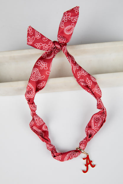 Red bandana with white patterns tied around a cylindrical object on a light gray background