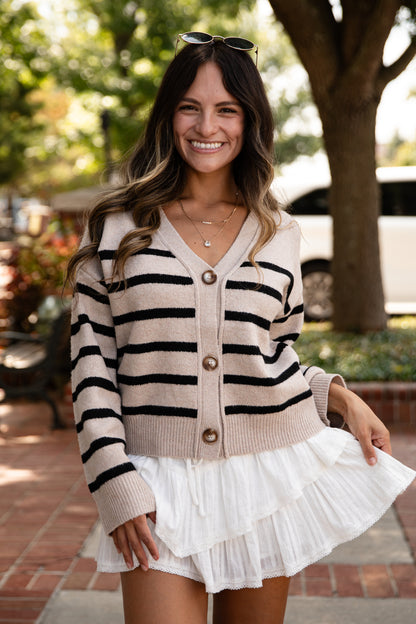 Woman wearing a striped sweater and white skirt outdoors