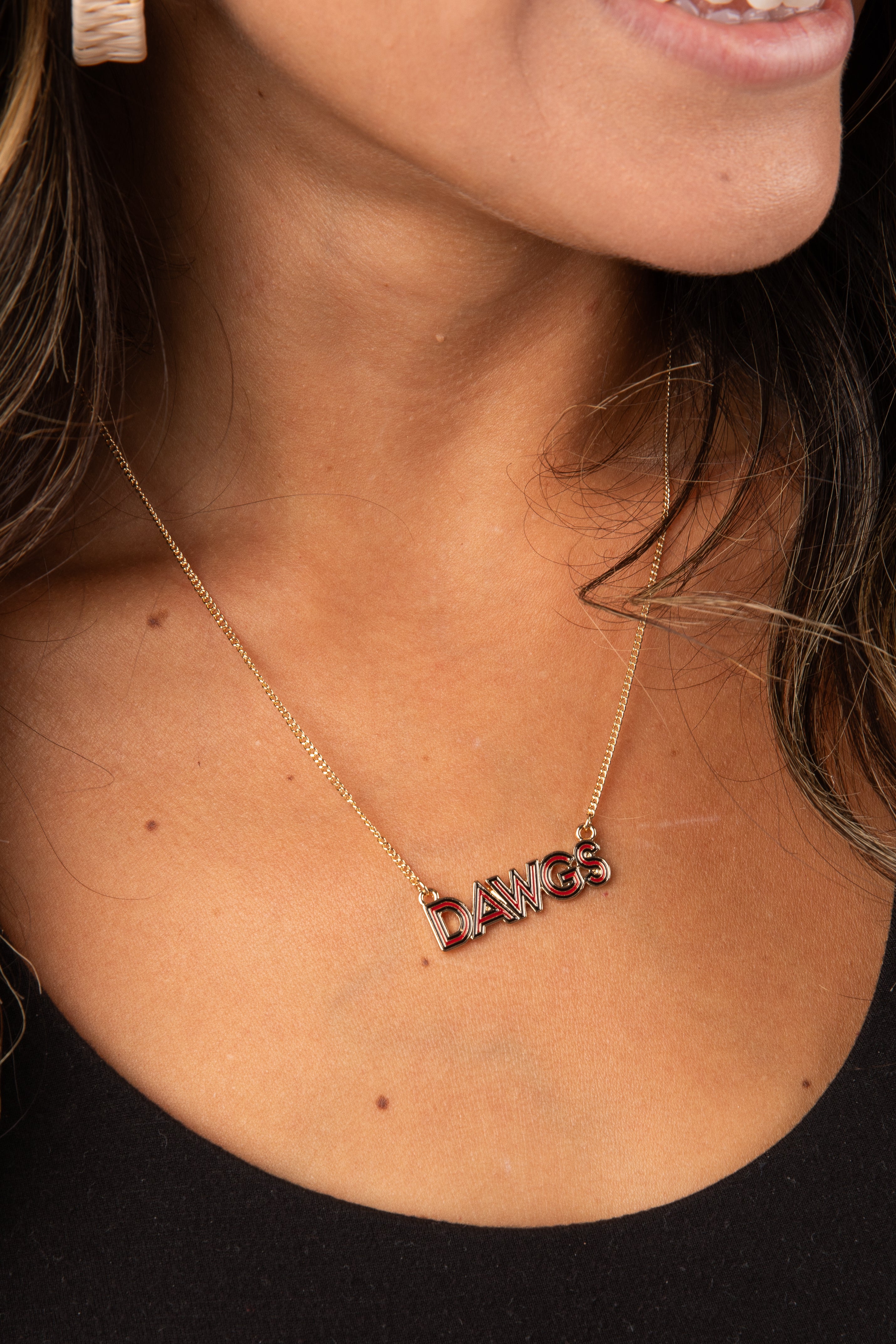 Close-up of a person wearing a gold necklace with a pendant.