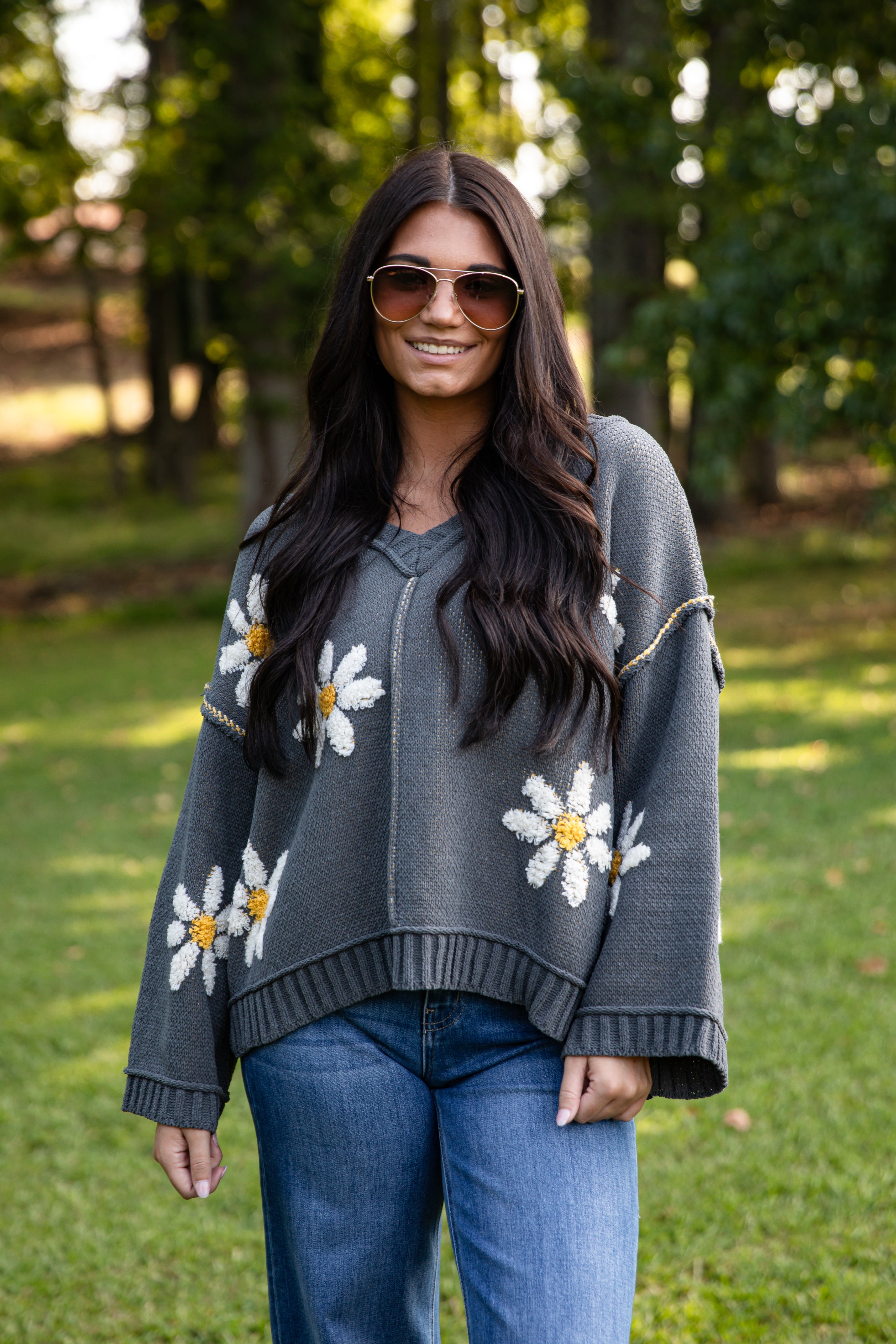 Woman wearing a gray sweater with floral patterns outdoors