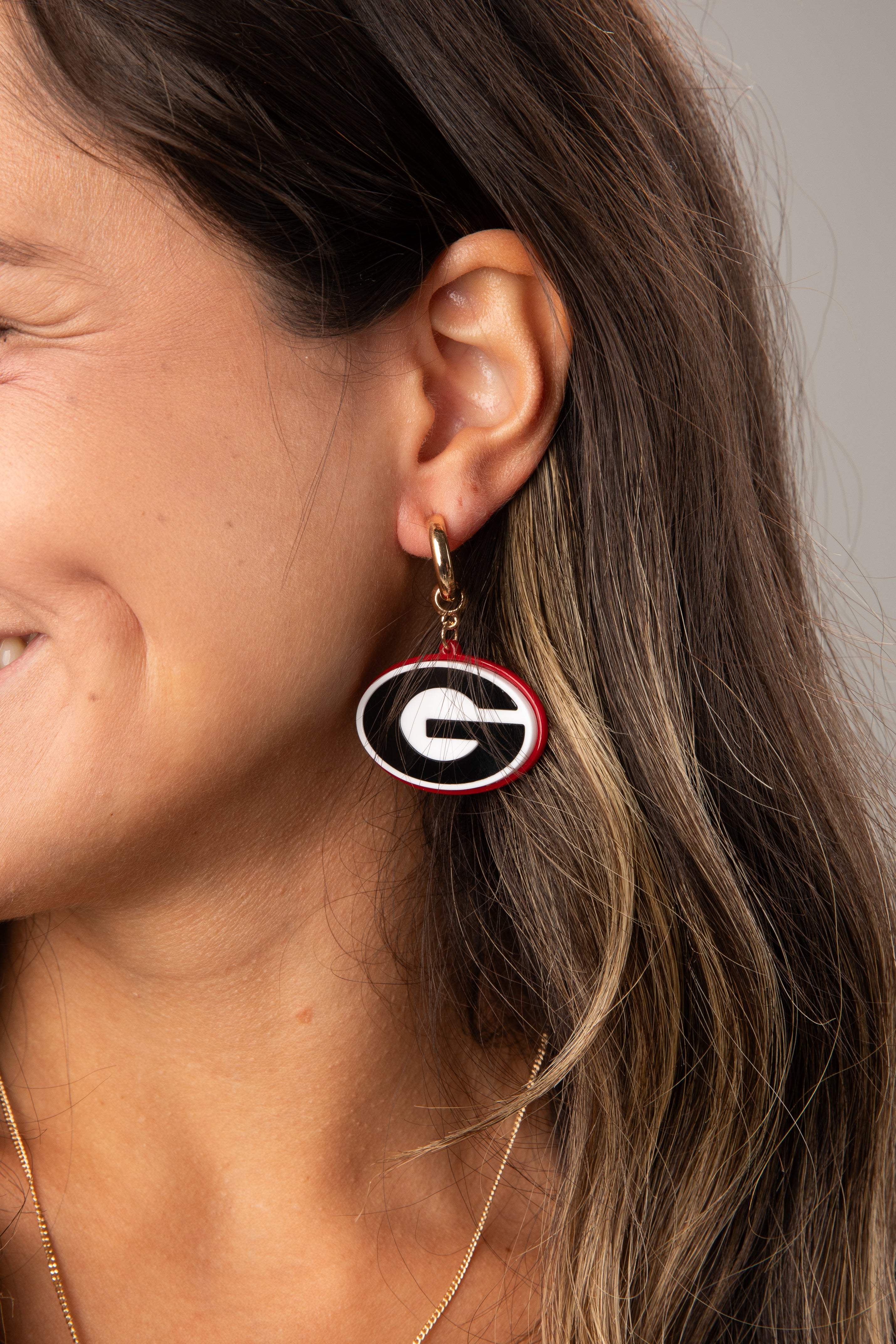 Close-up of a person wearing a Georgia Bulldogs earring with a neutral background