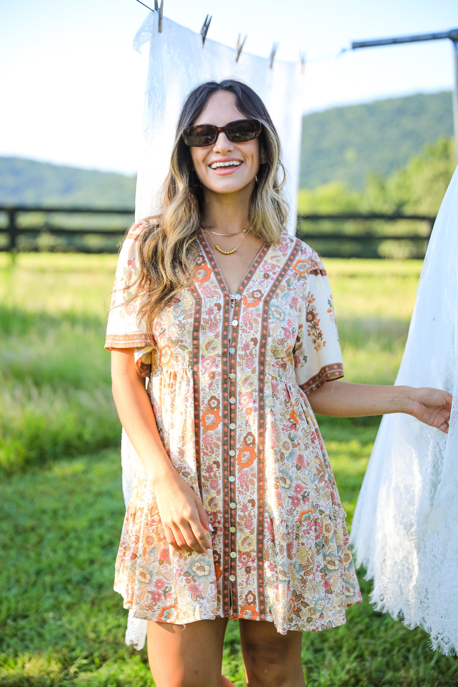 Woman wearing a floral dress standing outdoors with mountains in the background