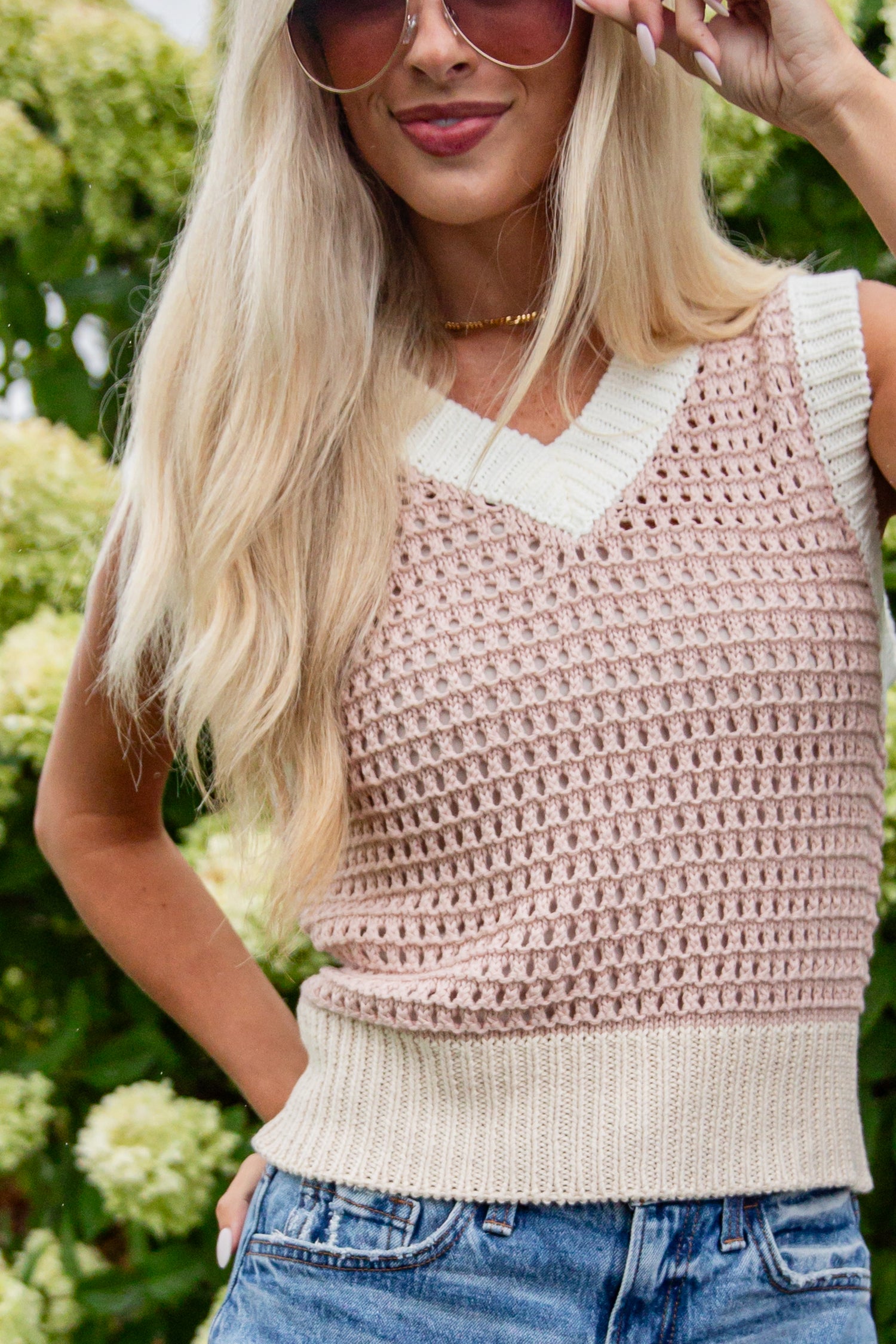 Woman wearing a pink crochet top with a white collar against a green background