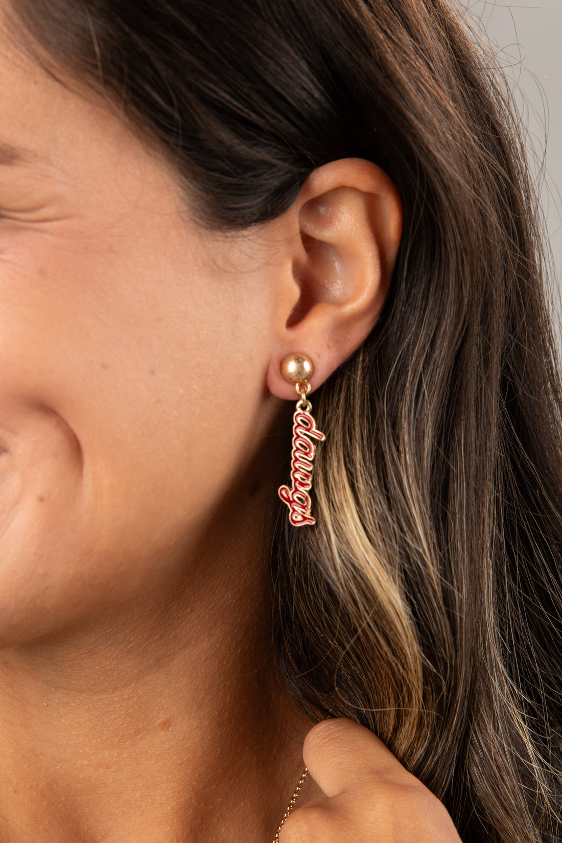 Close-up of an ear wearing a gold earring with &