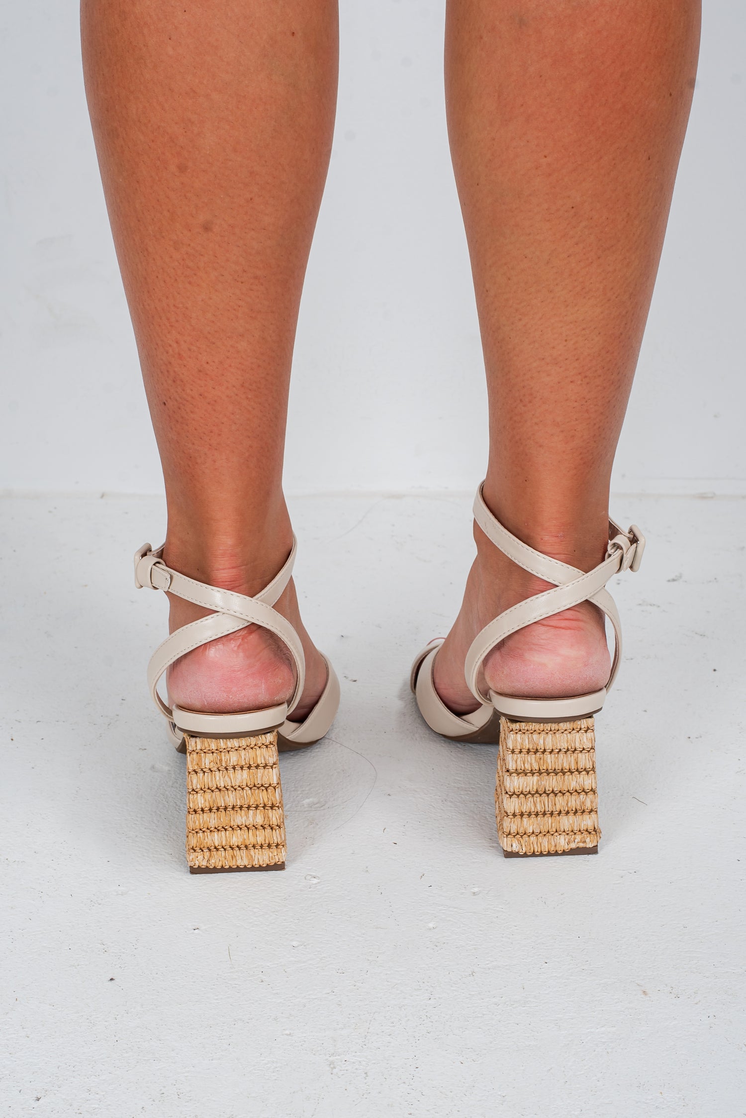 Beige high-heeled sandals with woven block heels on a white background