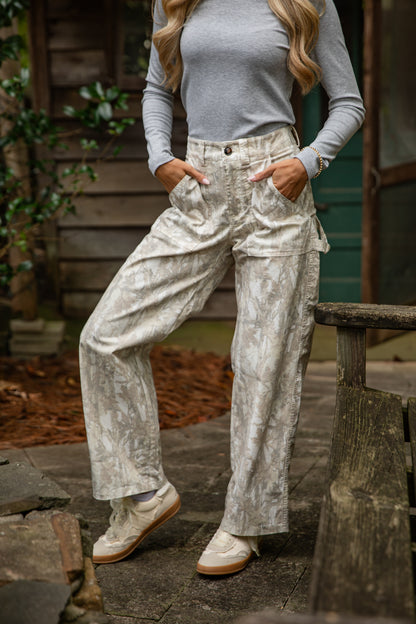 Person wearing a gray long-sleeve top and light-colored pants standing outdoors.