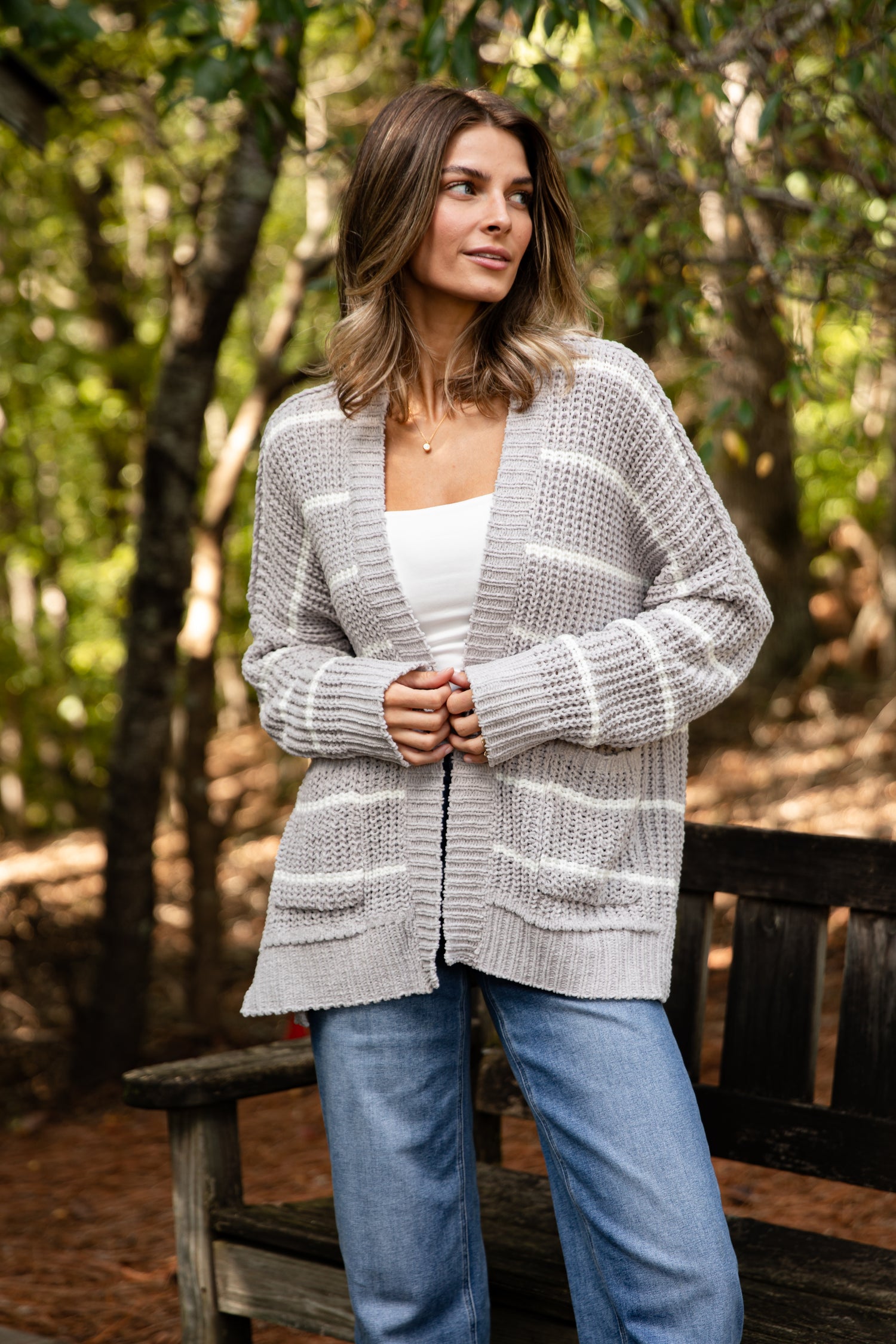 Woman wearing a gray cardigan in a forest setting