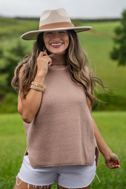 Woman wearing a beige sweater and hat in a green field