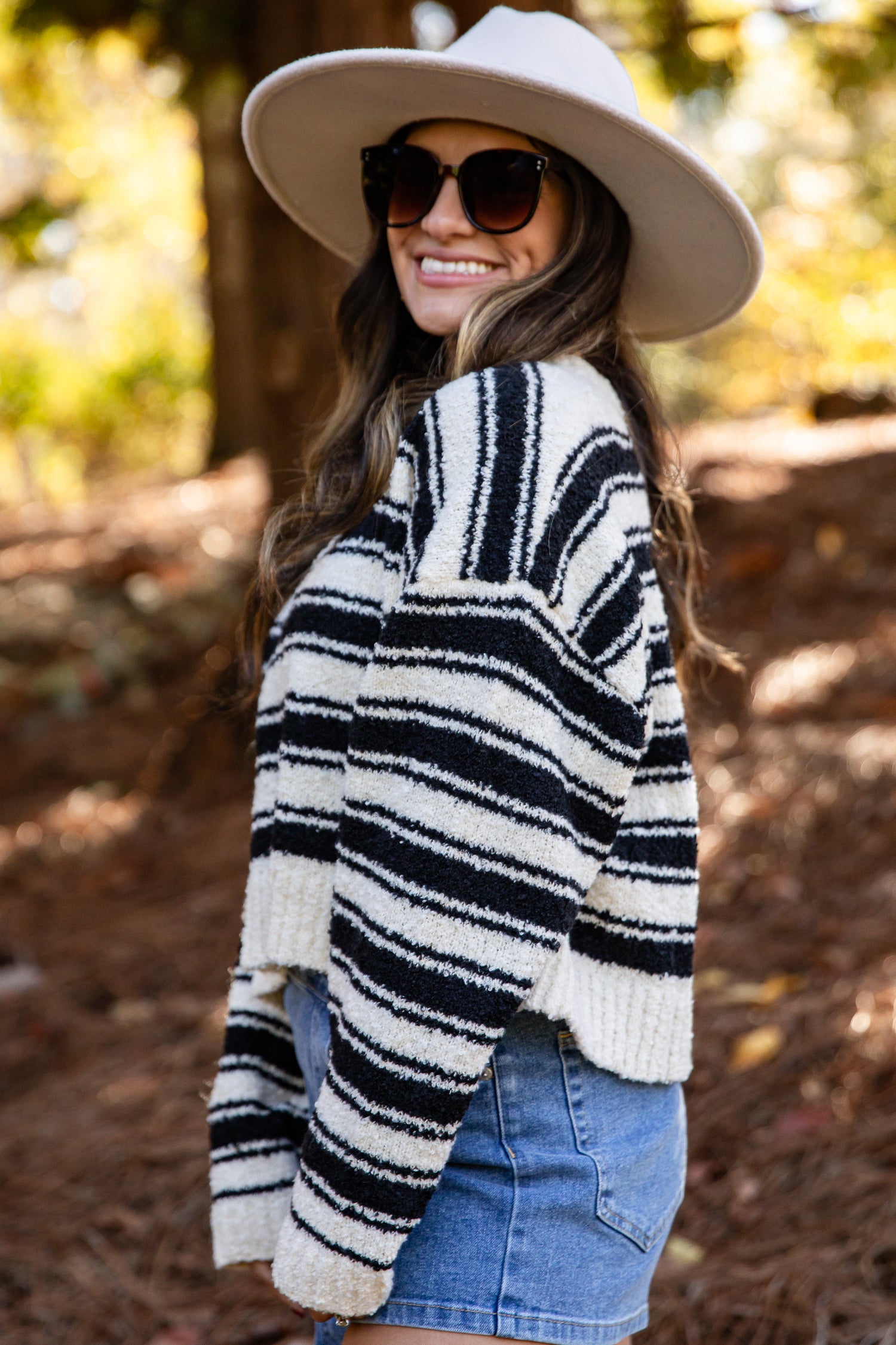 Woman wearing a striped sweater and hat in a forest setting