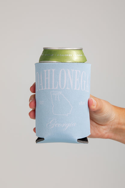 Hand holding a can with a blue sleeve featuring text and a map on a gray background