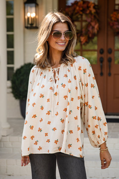 Woman wearing a floral blouse and sunglasses outdoors.