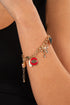 Gold bracelet with charms on a wrist against a black background