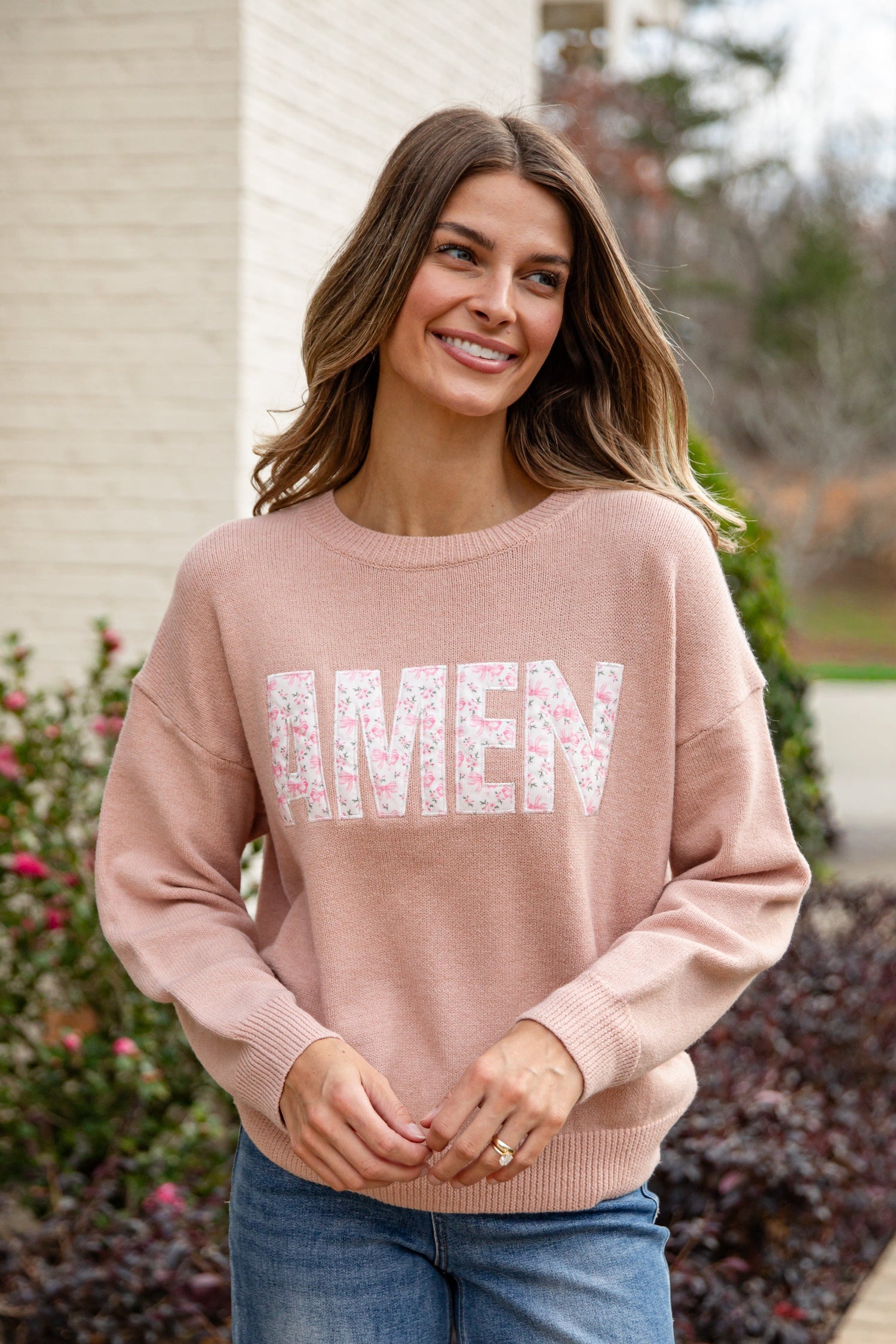 Woman wearing a pink sweater with &