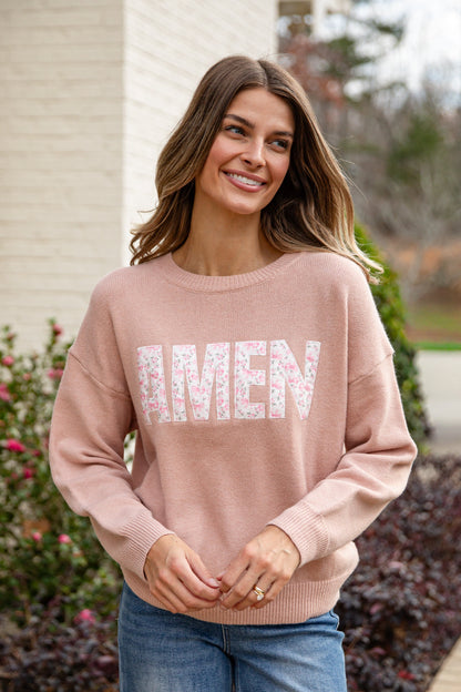 Woman wearing a pink sweater with &