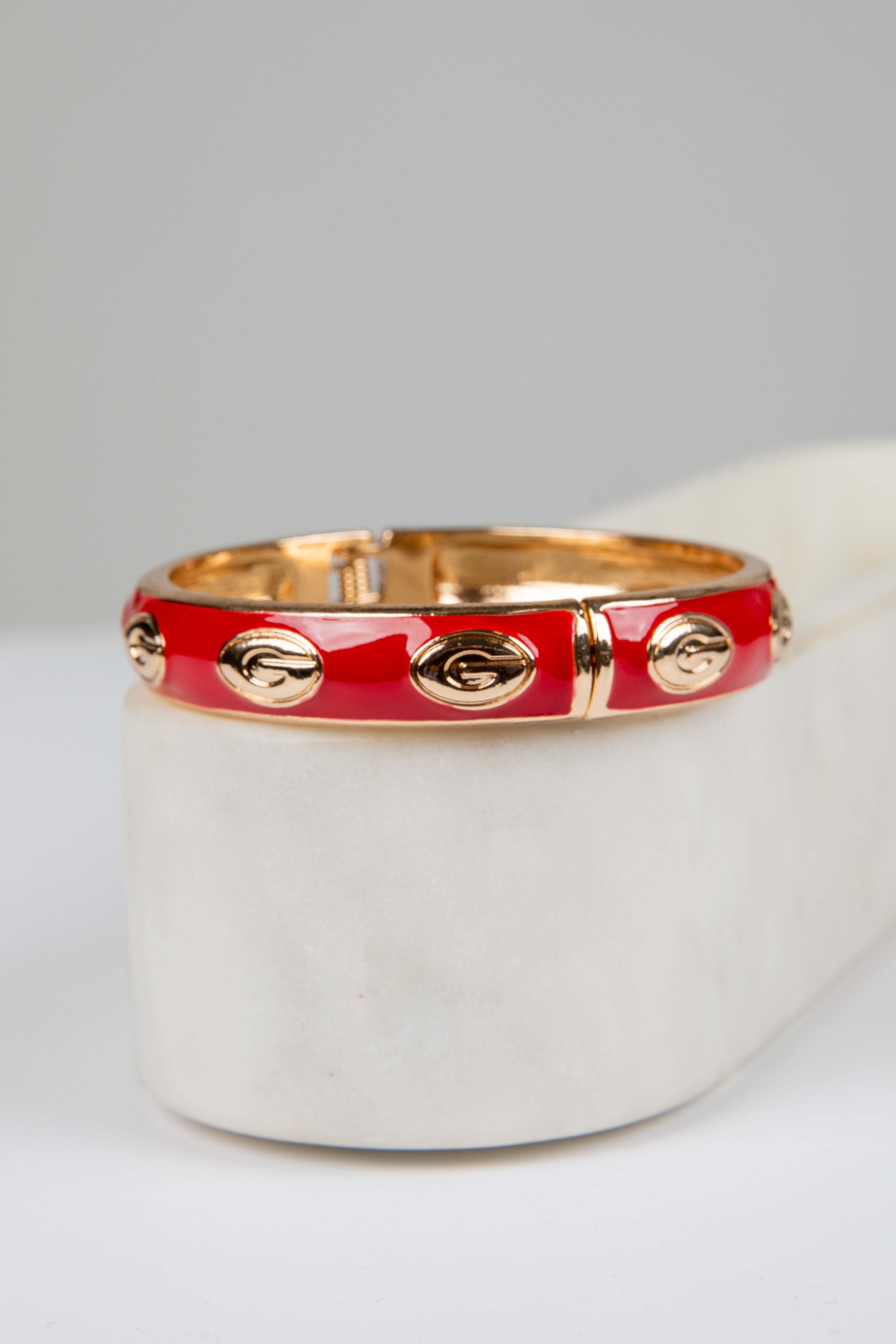 Red bracelet with gold accents on a white surface