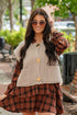 Woman wearing a plaid dress over a beige cardigan with sunglasses outdoors.