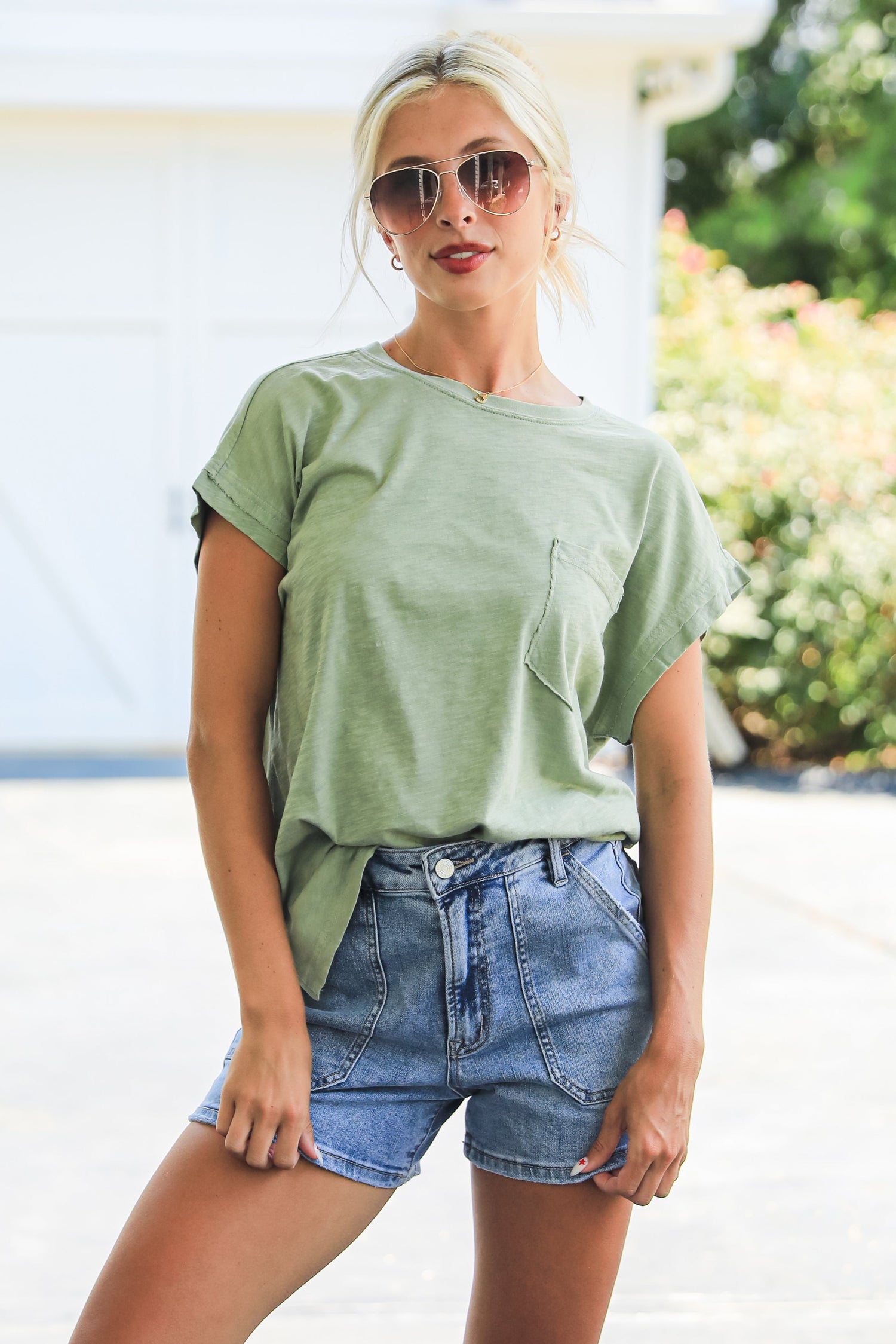 Woman wearing a green t-shirt and denim shorts outdoors