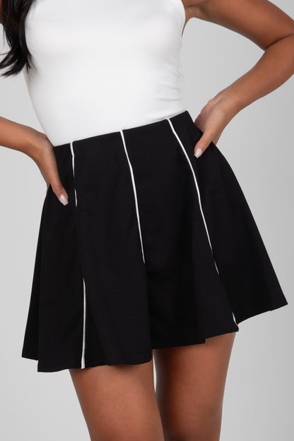 Black skirt with white trim worn by a person on a plain background