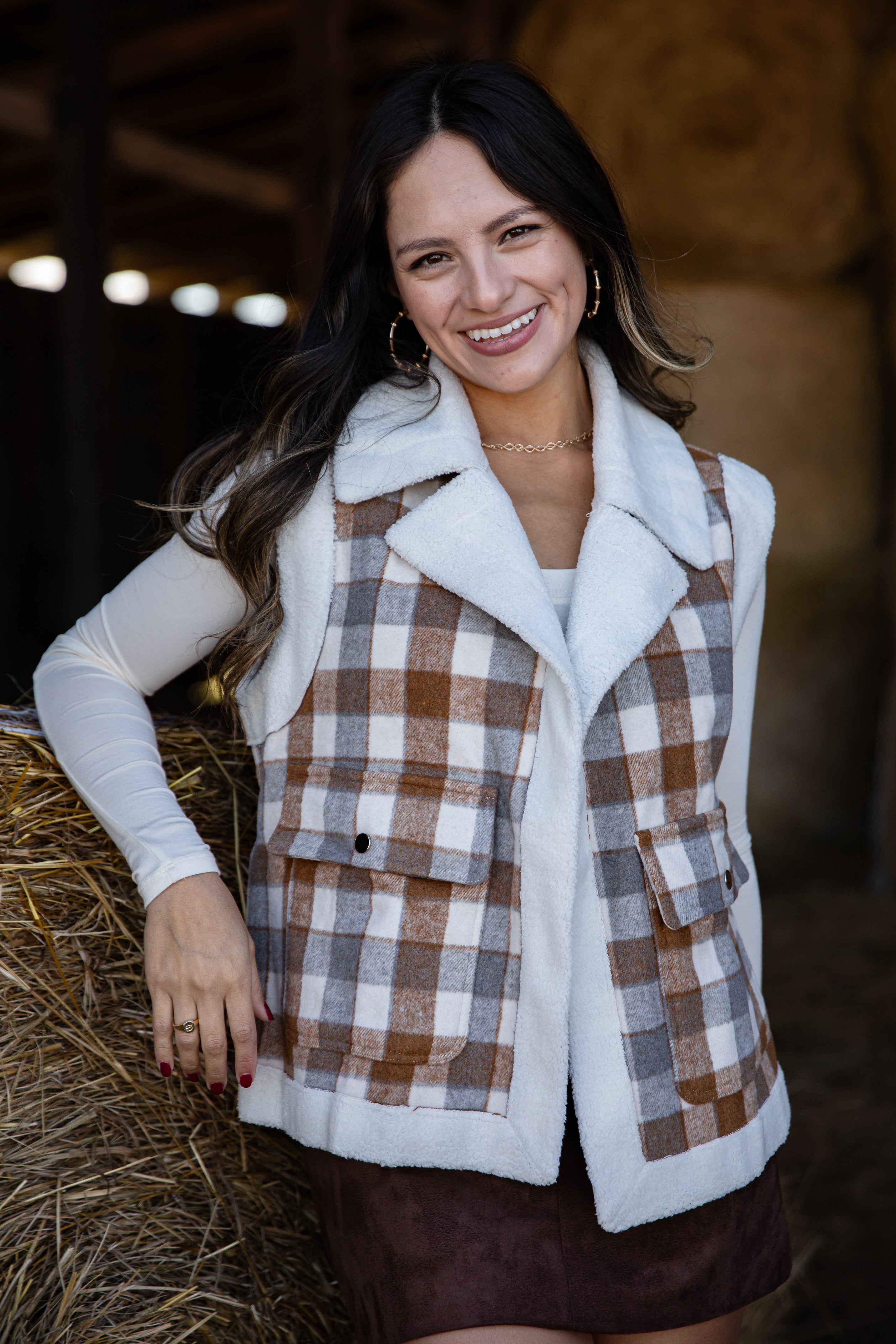 Woman wearing a plaid vest with a white collar in a barn setting