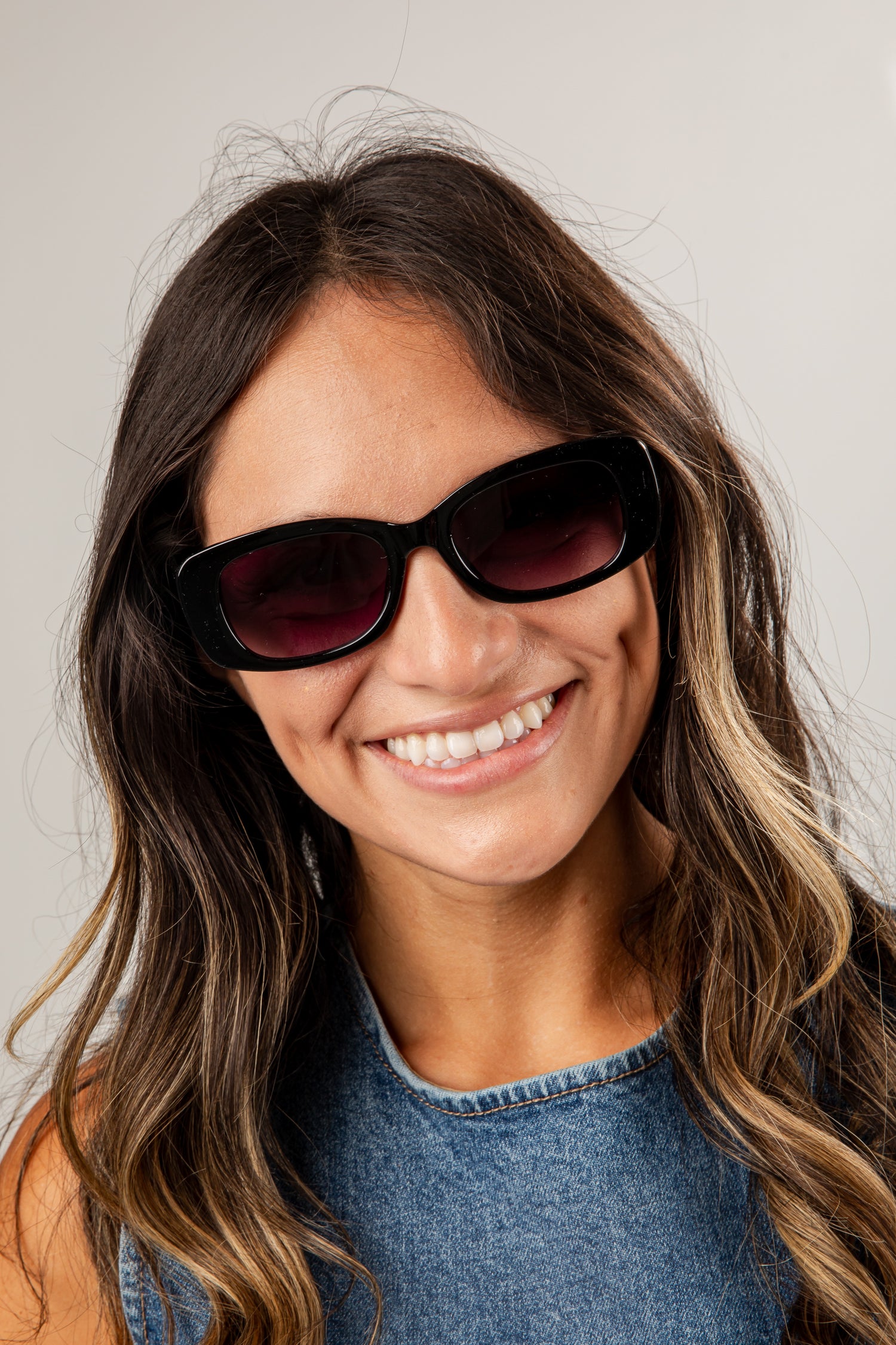 Woman wearing dark sunglasses with a plain background