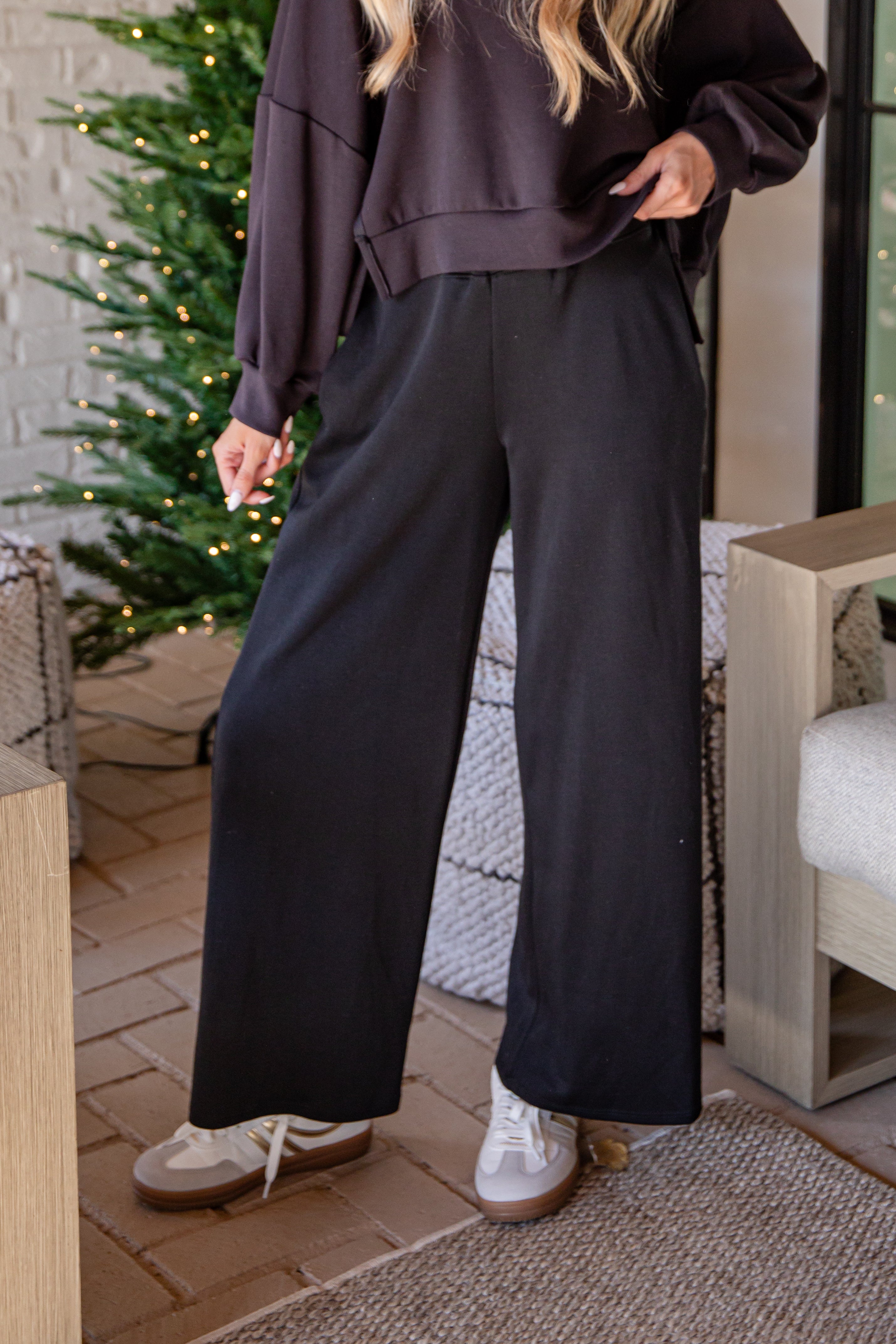 Person wearing a dark outfit with wide-leg pants standing in an outdoor setting.