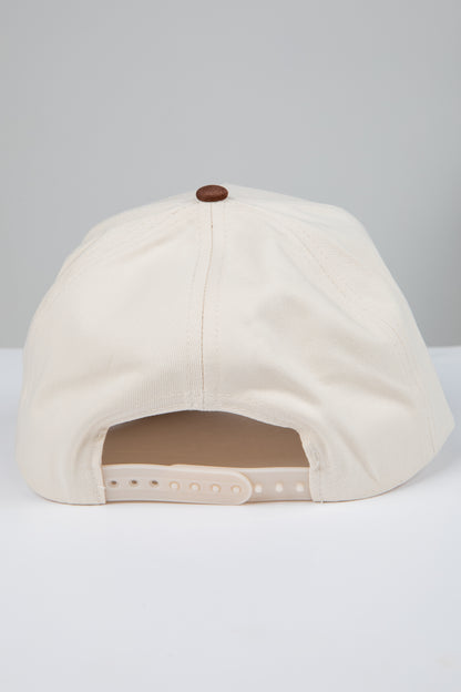Beige baseball cap with a brown button on a light gray background