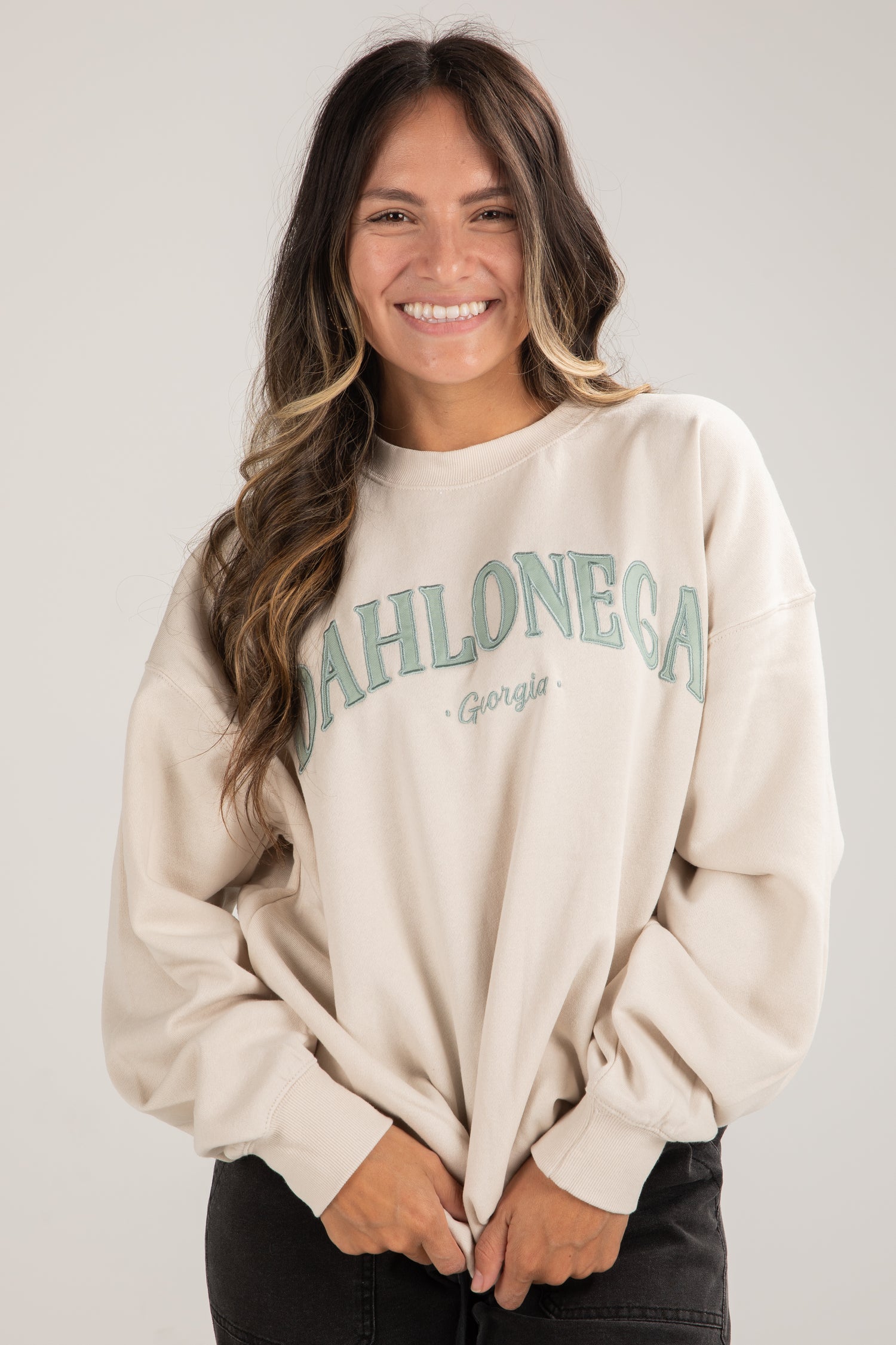 Woman wearing a beige sweatshirt with &