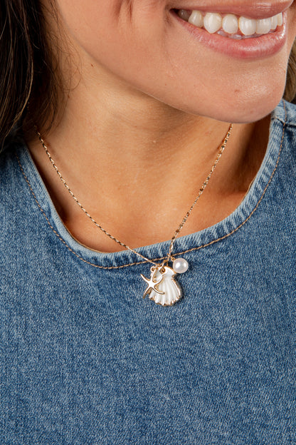 Close-up of a person wearing a necklace with a pendant, set against a denim background.