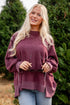 Woman wearing a maroon sweater standing in front of trees