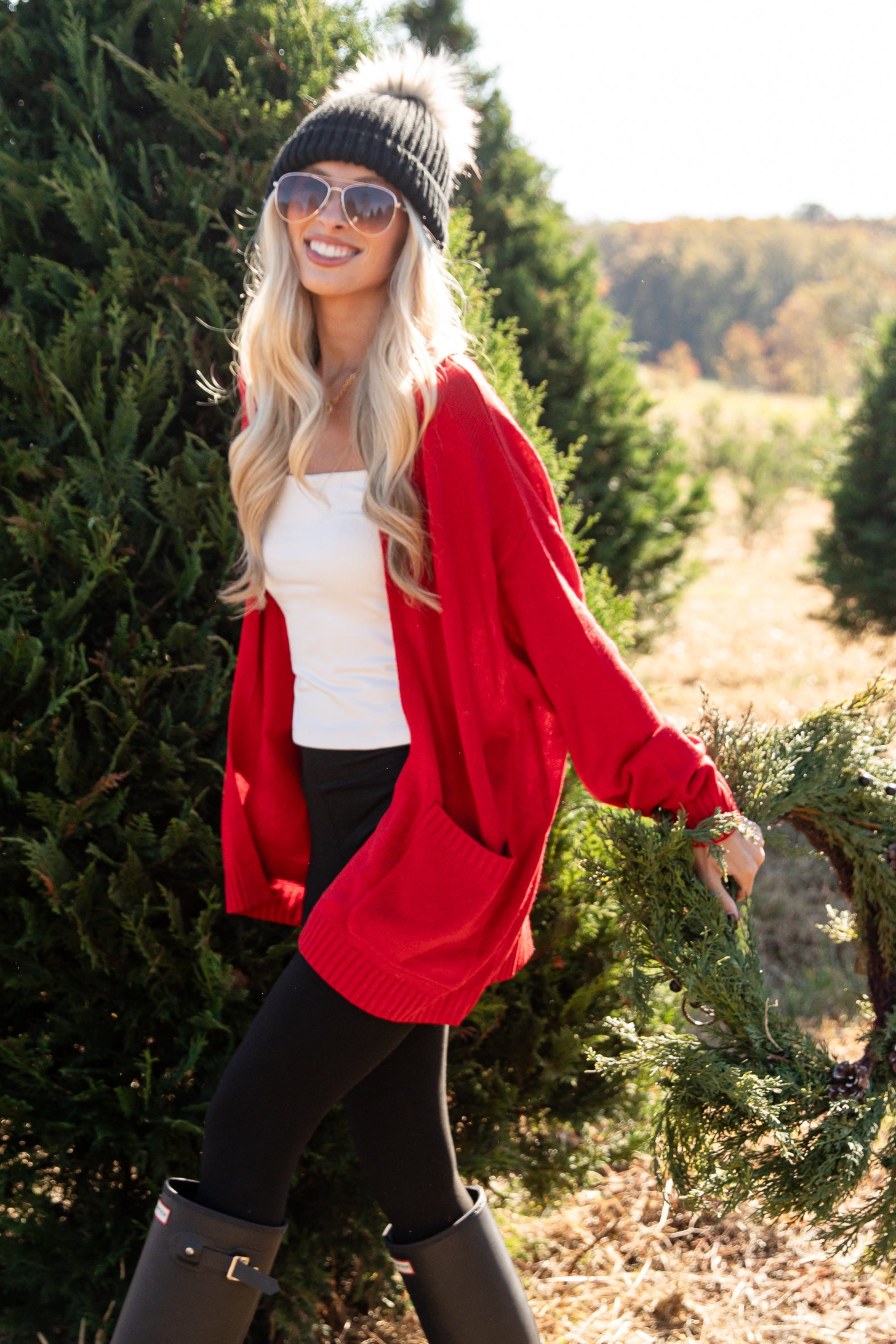 Woman holding a Christmas wreath in a tree farm