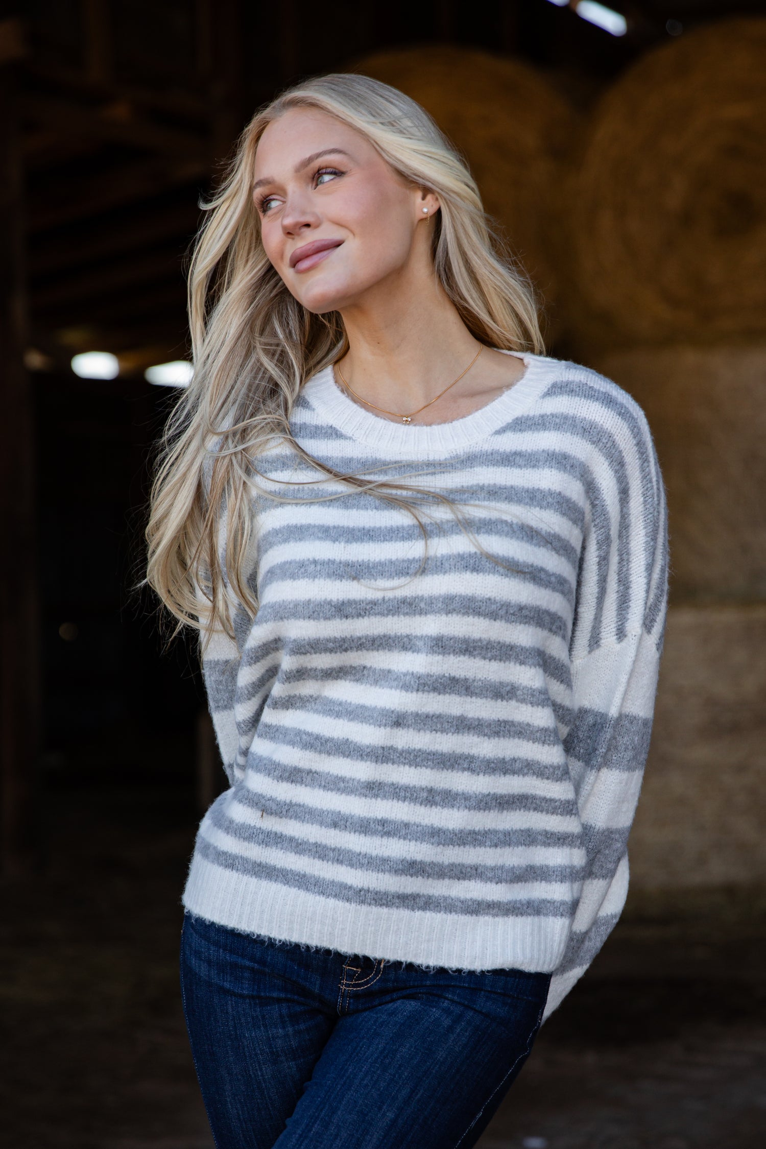 Woman wearing a striped sweater in a barn setting