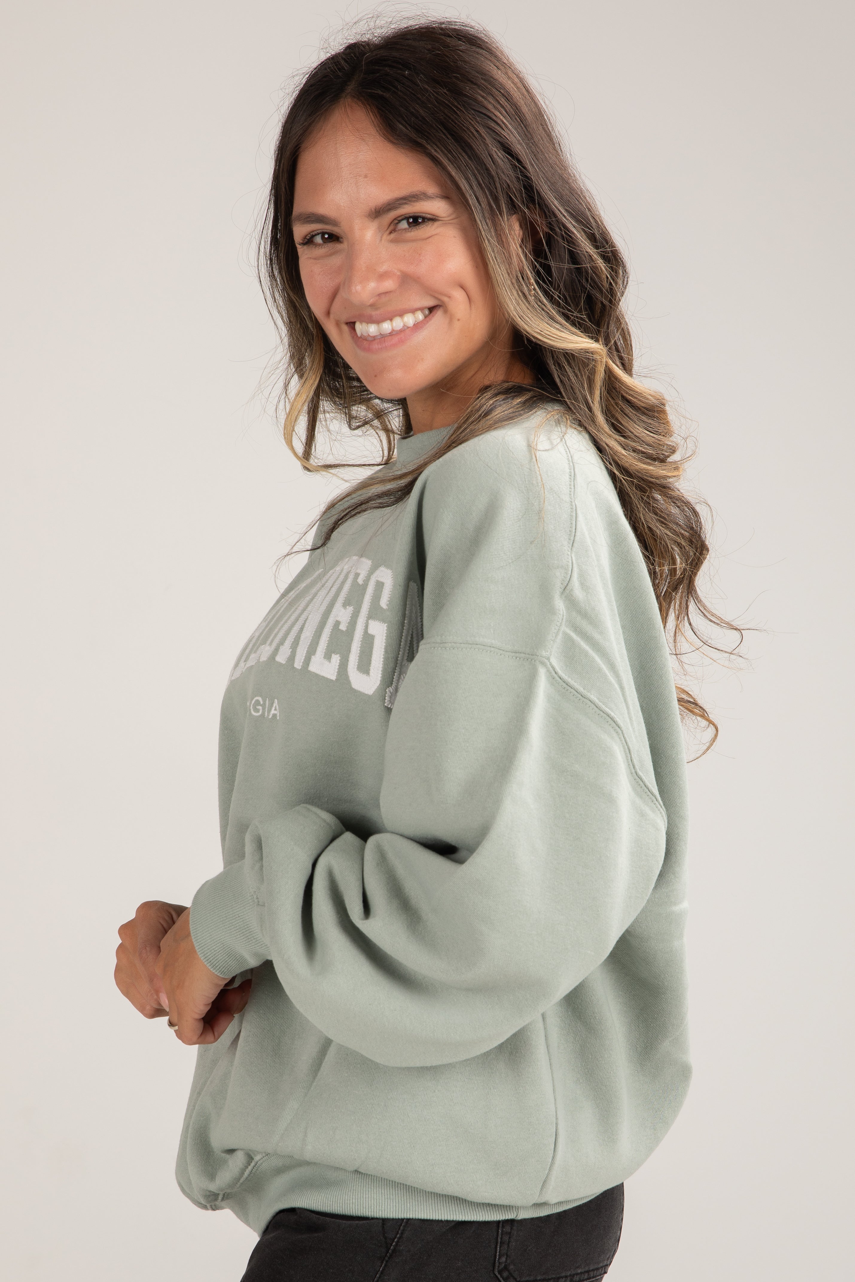 Woman wearing a light green sweatshirt with text on a plain background