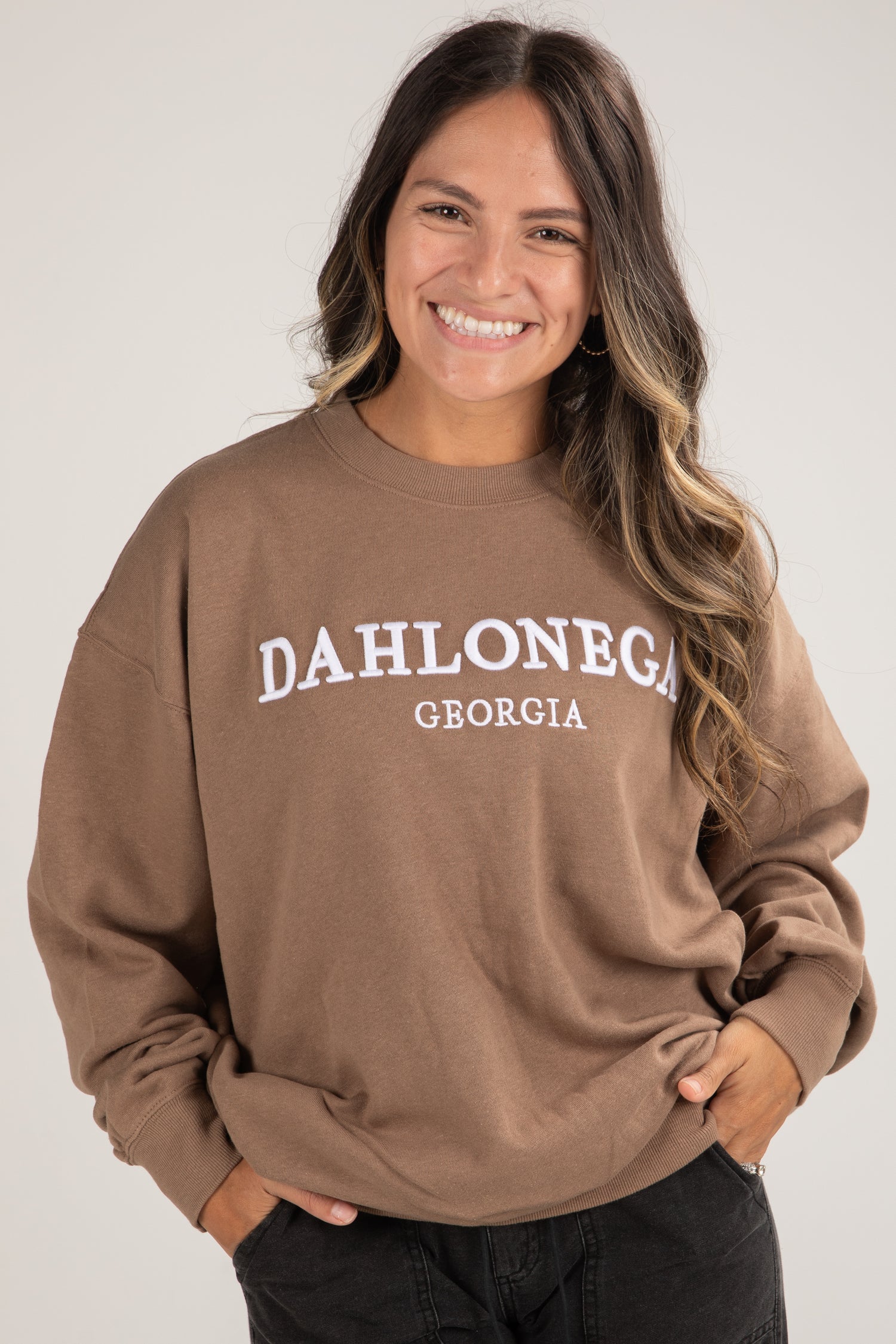 Woman wearing a brown sweatshirt with &