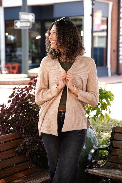 Woman wearing a beige cardigan in an outdoor setting