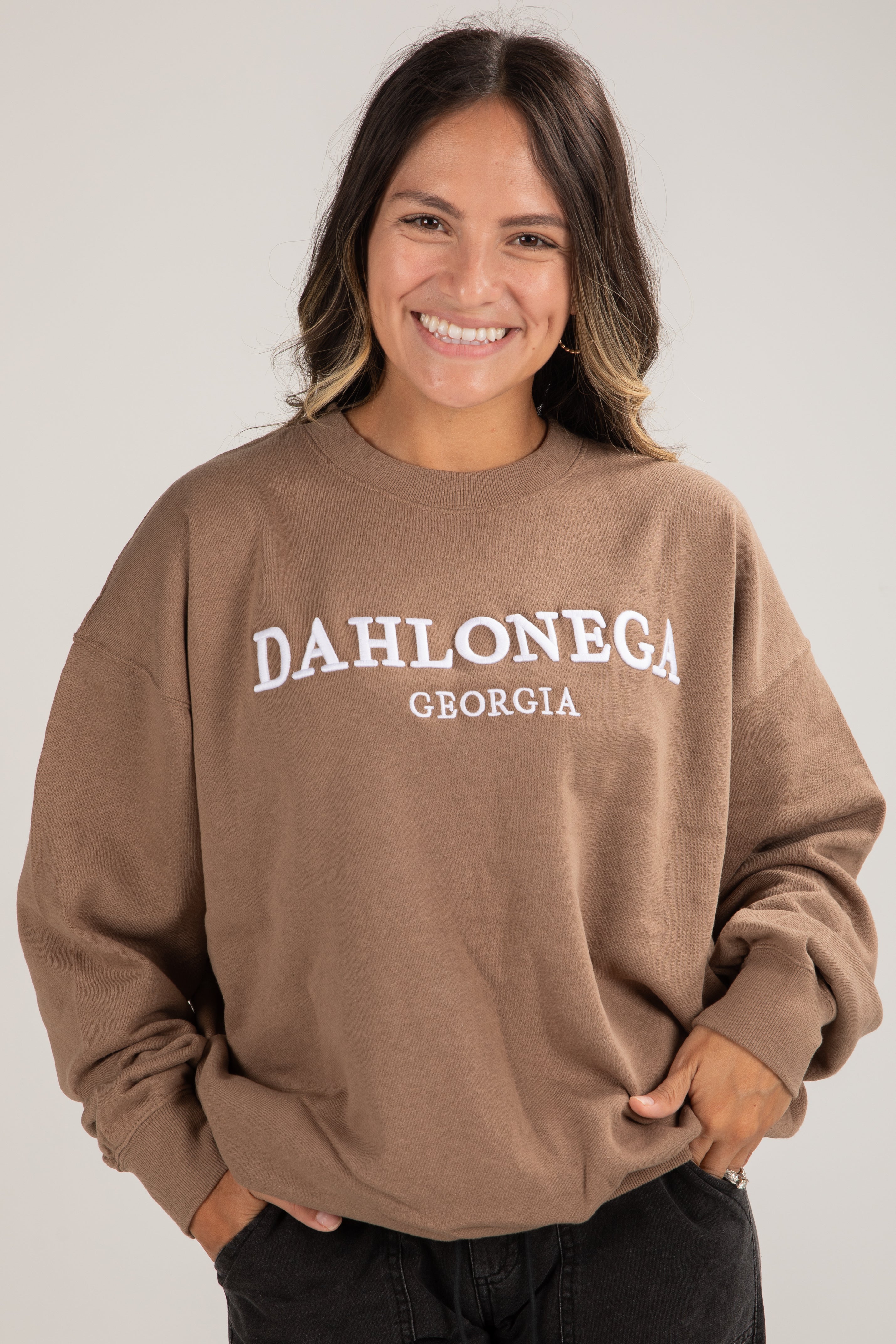 Person wearing a brown sweatshirt with &