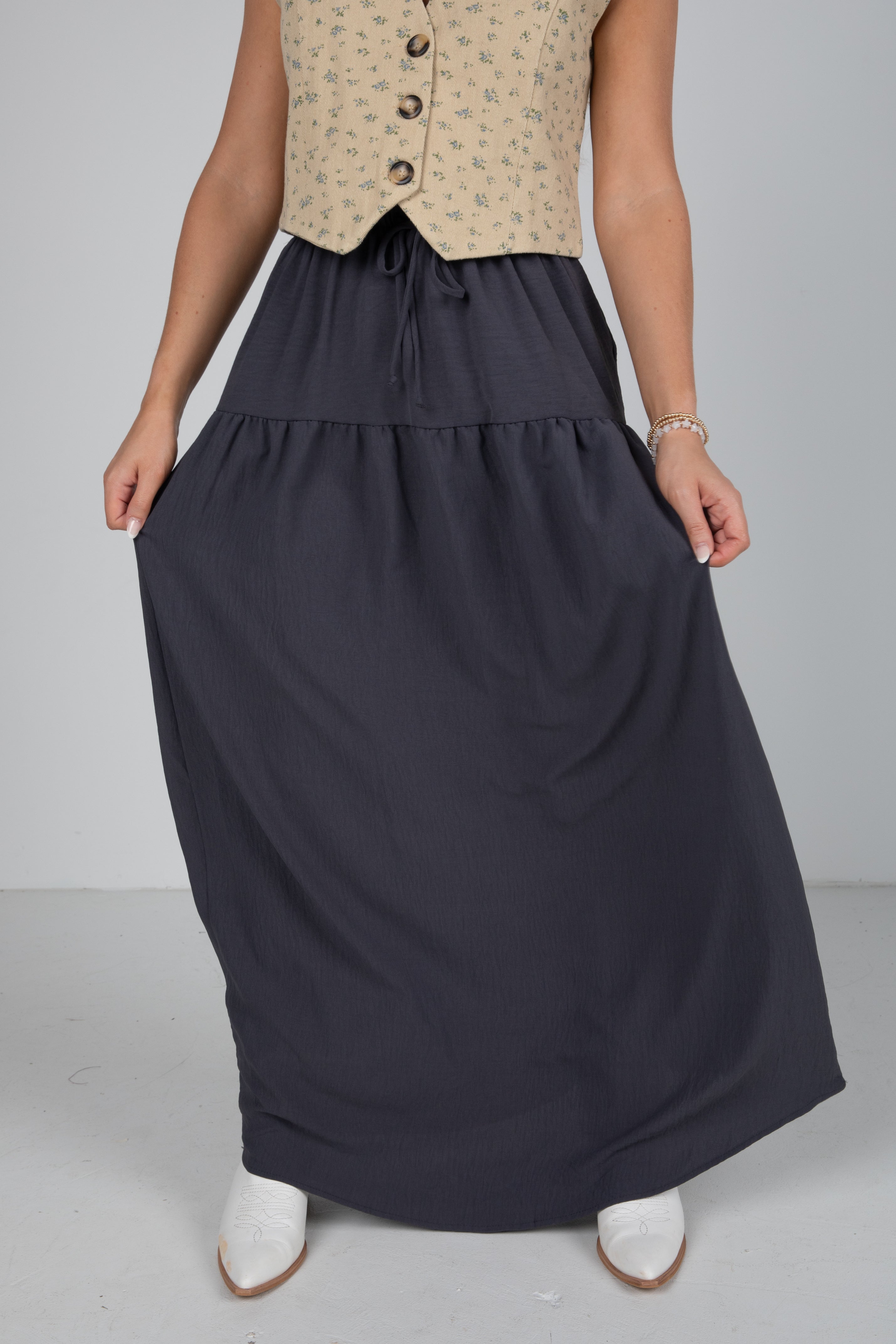 Person wearing a long navy skirt with a plain background
