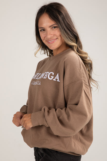 Woman wearing a brown sweatshirt with text on a plain background