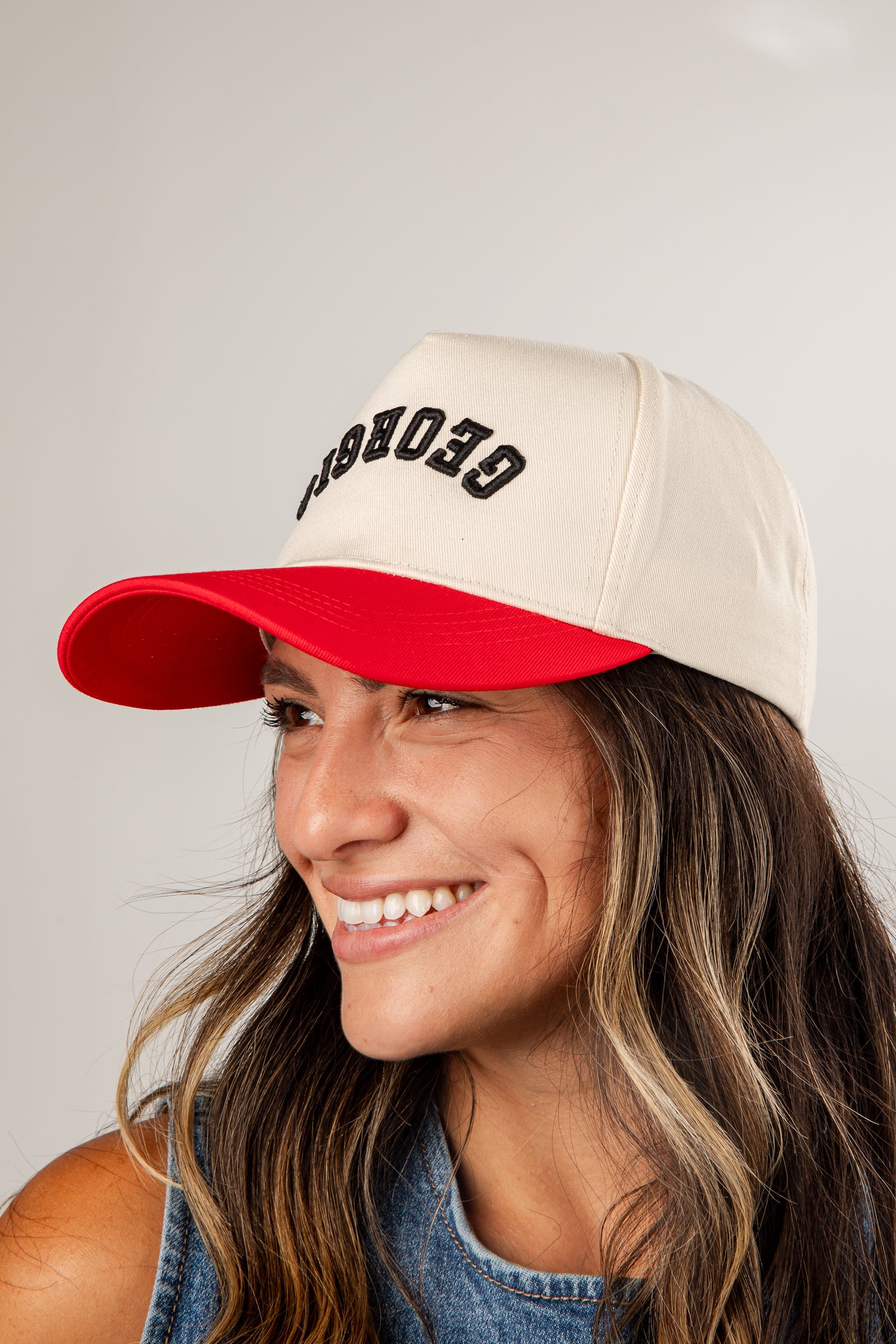 Woman wearing a beige and red cap with &
