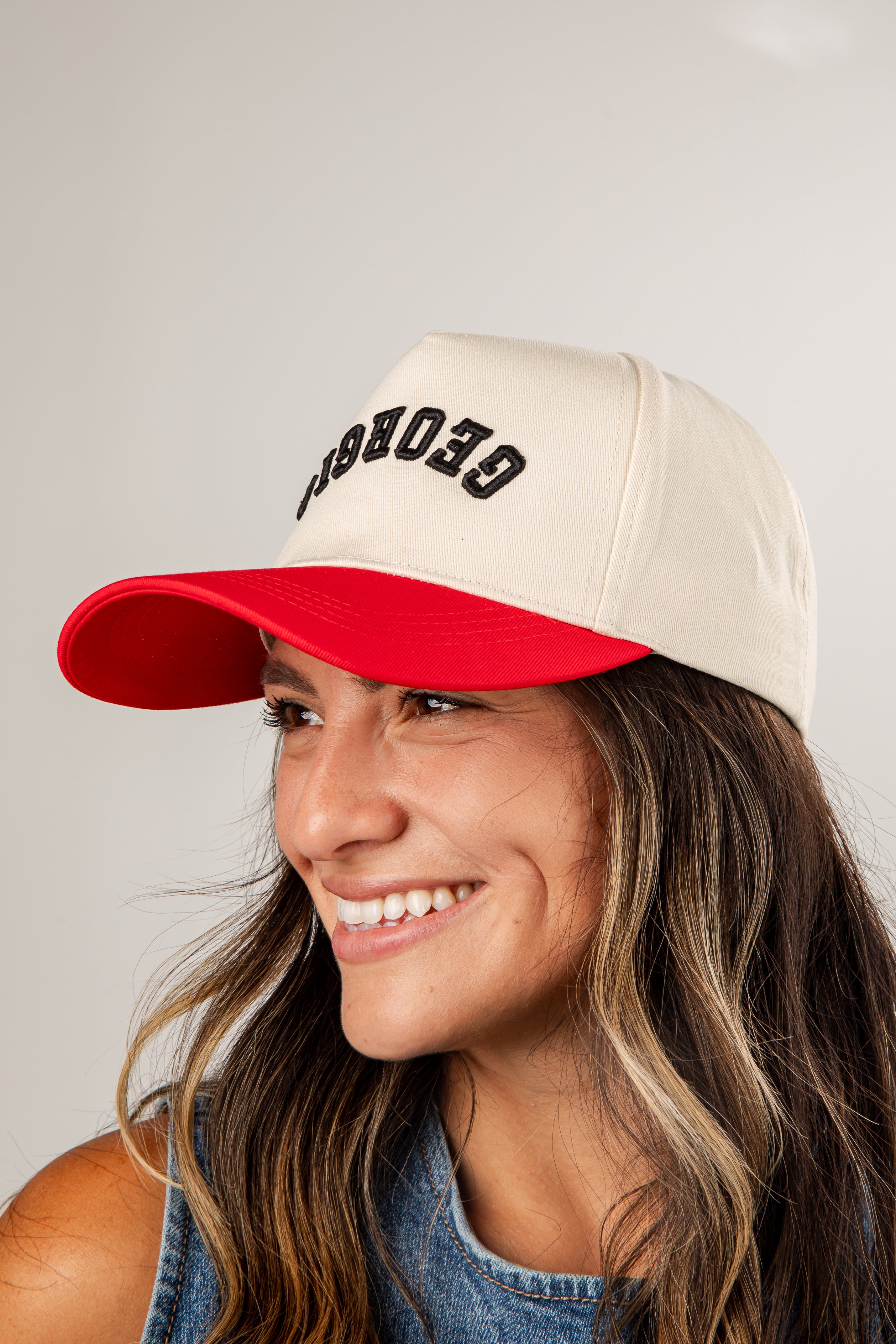Woman wearing a beige and red cap with &