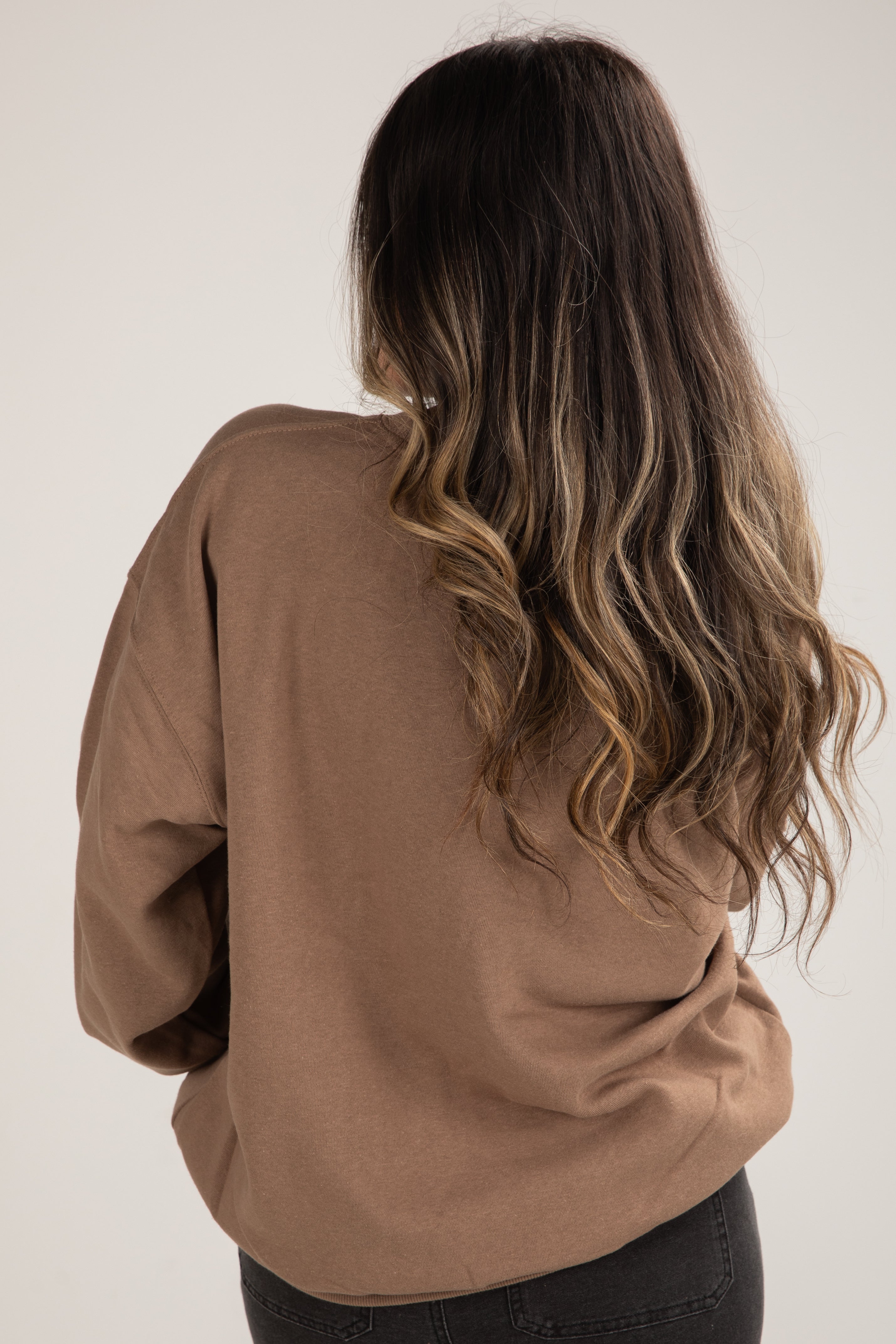 Person wearing a brown sweater with a plain background
