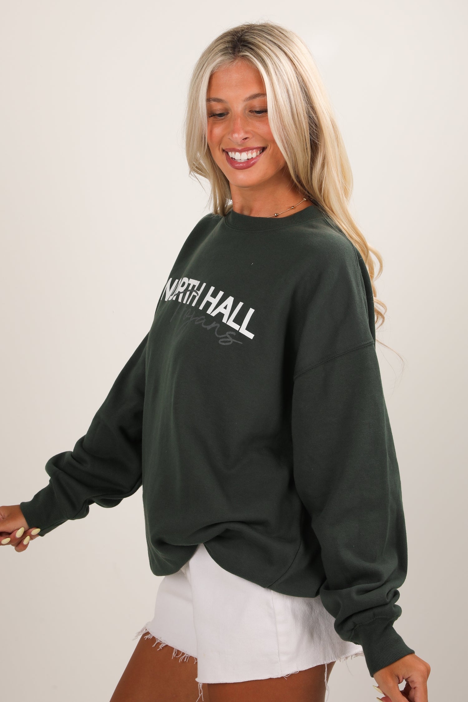 Woman wearing a dark green sweatshirt with &