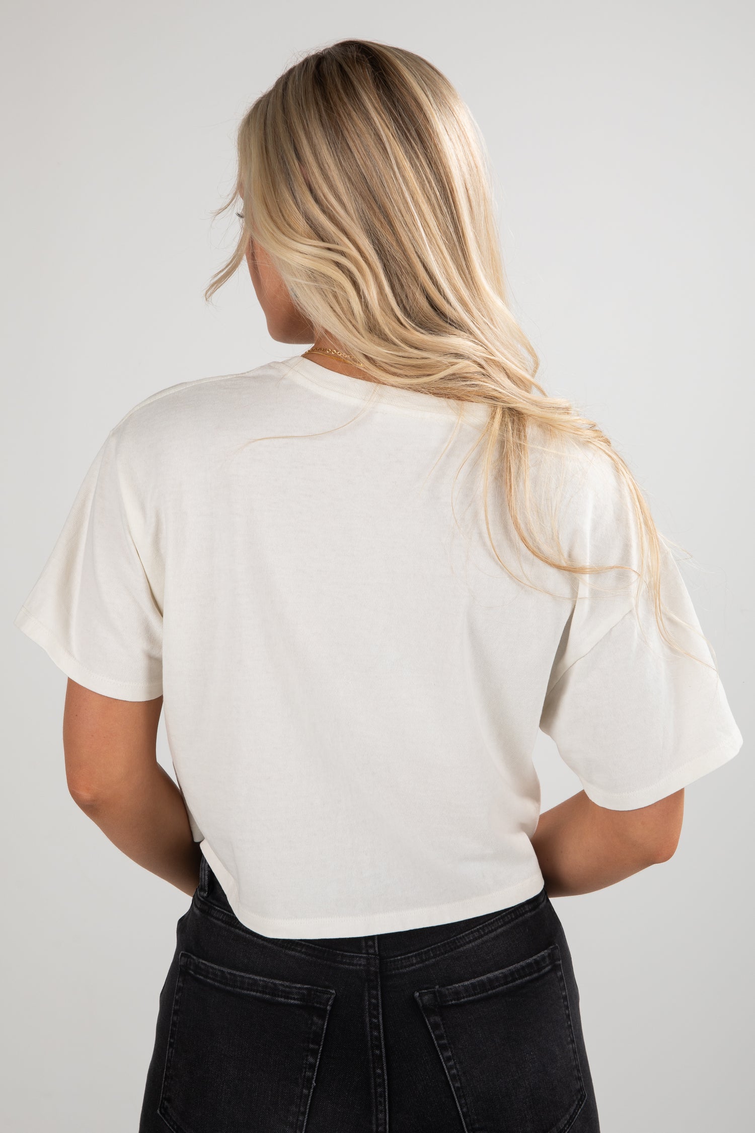 Person wearing a white t-shirt and black pants against a plain background