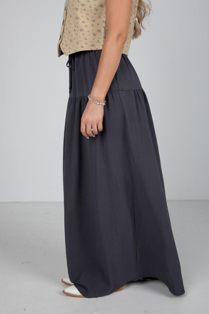 Person wearing a long dark blue skirt on a plain background