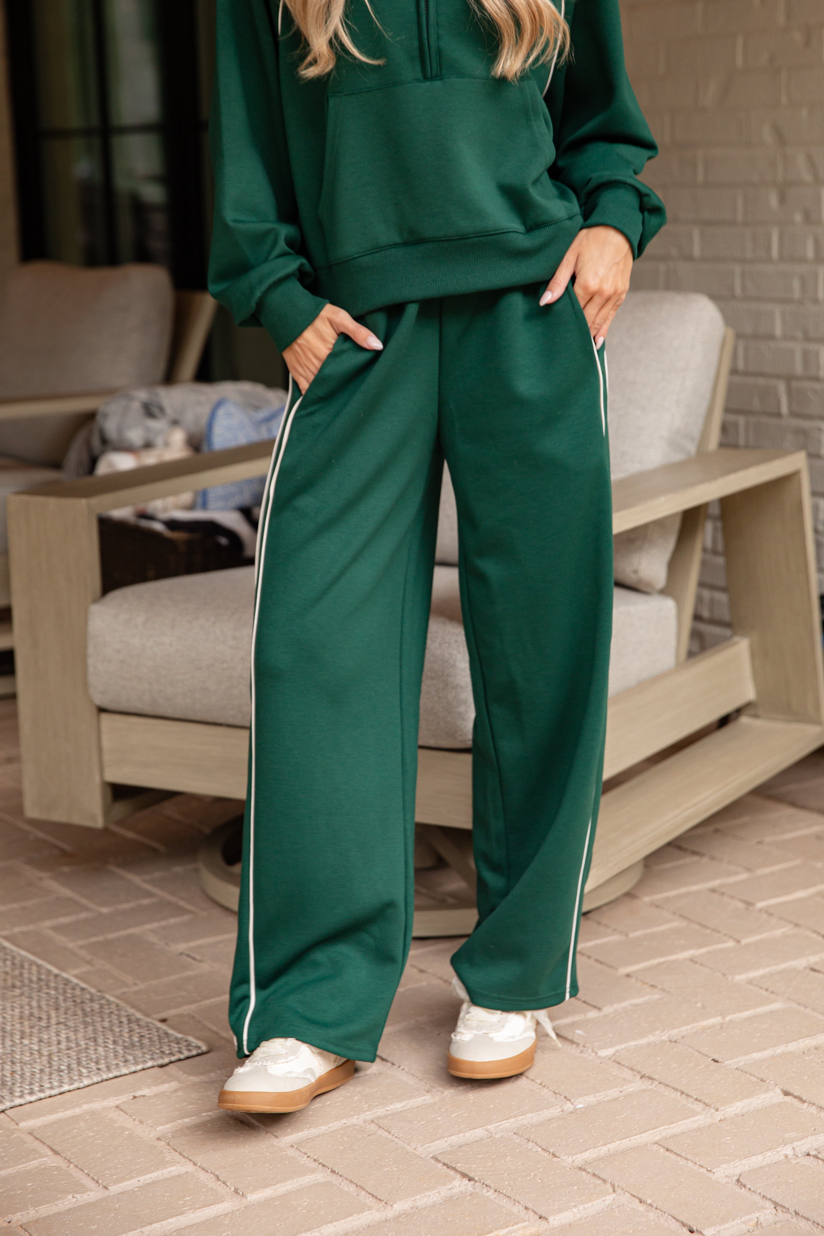 Person wearing a green tracksuit standing on a patio.