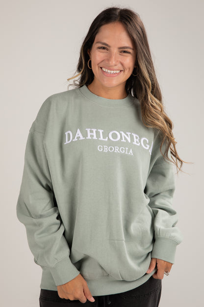 Woman wearing a light green sweatshirt with &