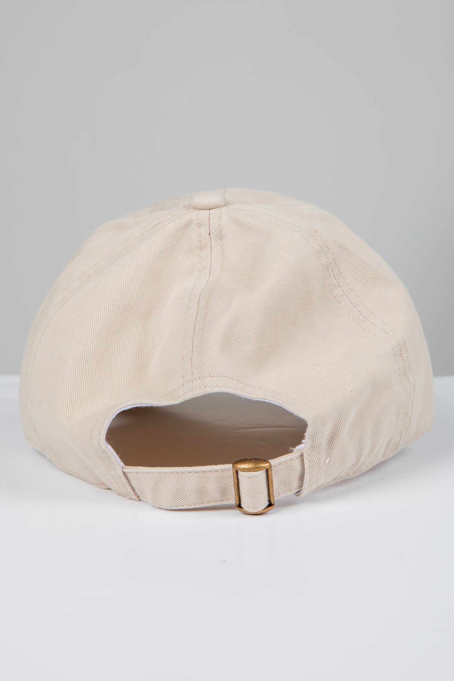 Beige baseball cap with brown patch on a light gray background