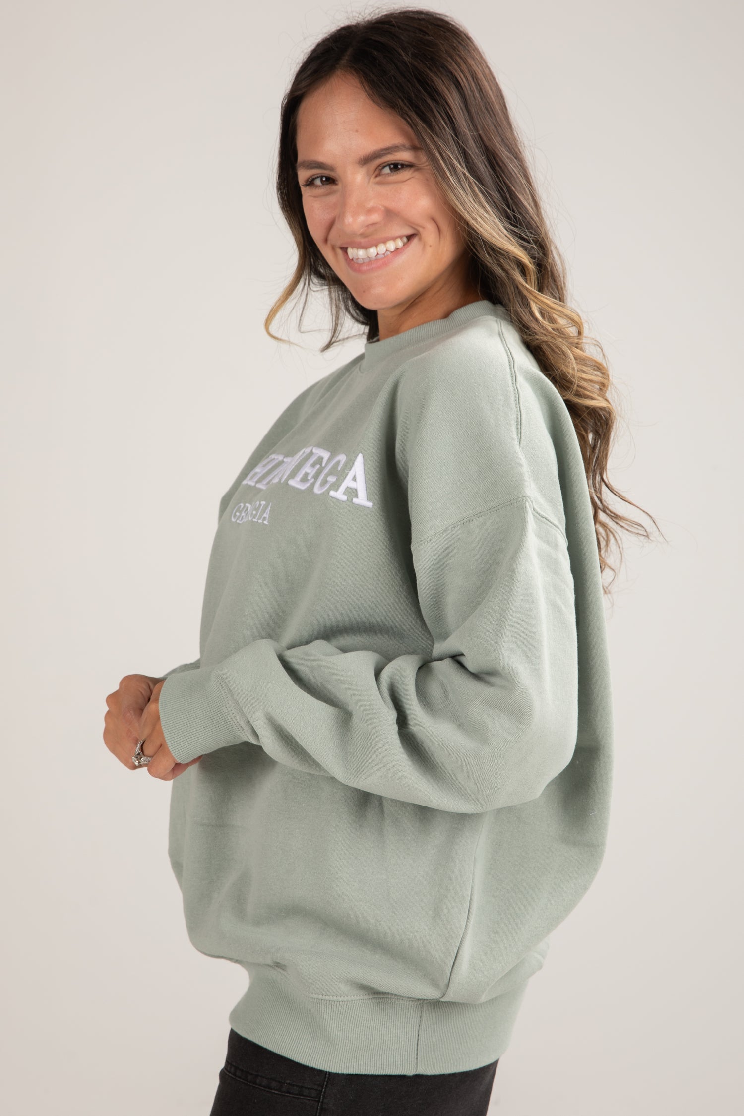 Woman wearing a light green sweatshirt with text on a plain background