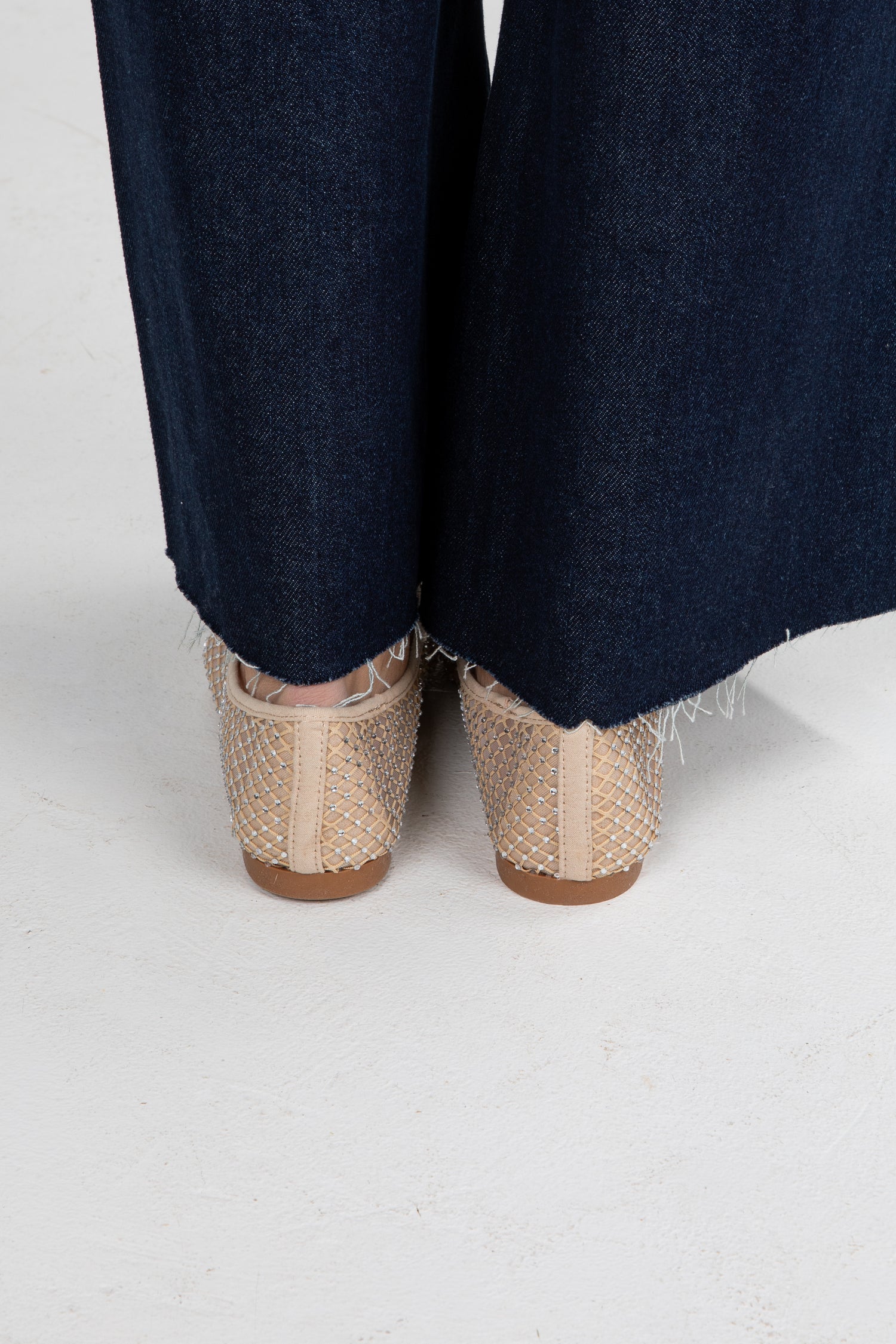 Navy pants with beige woven shoes on a white background